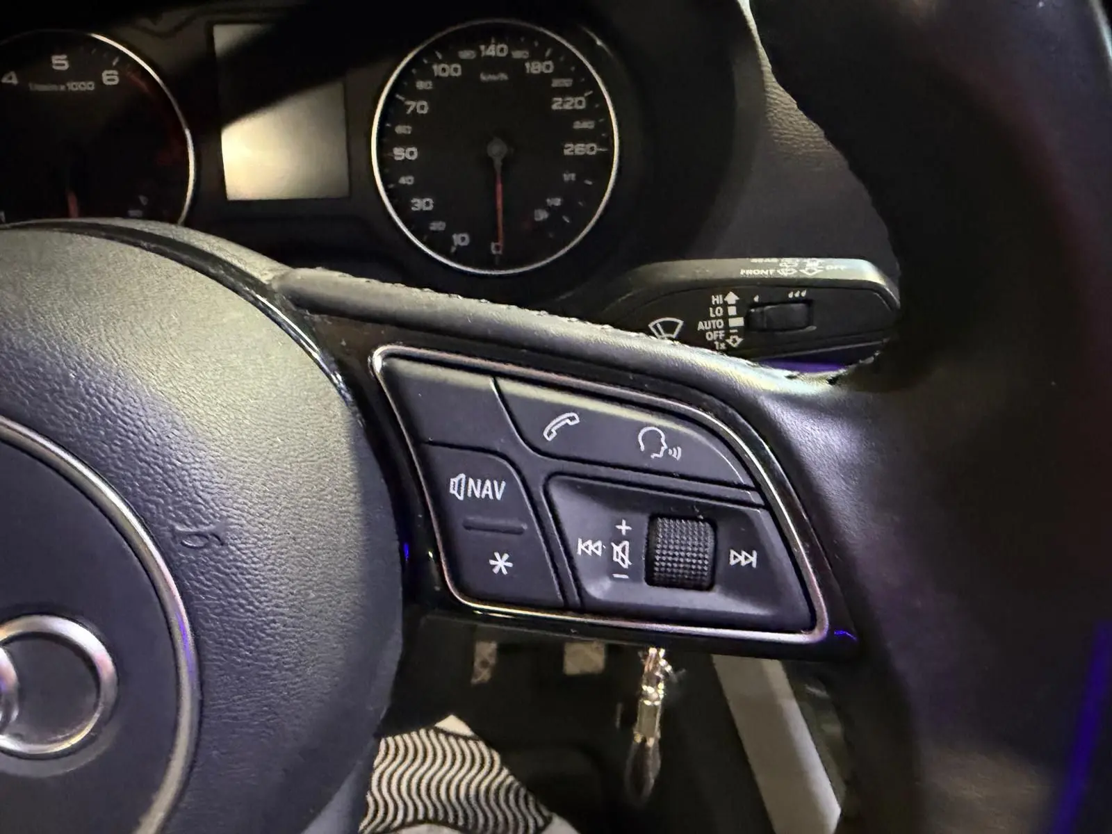 Gros plan sur le volant cuir multifonctions côté droit de l’Audi Q2 1.0 TFSI gris avec commandes audio et navigation.