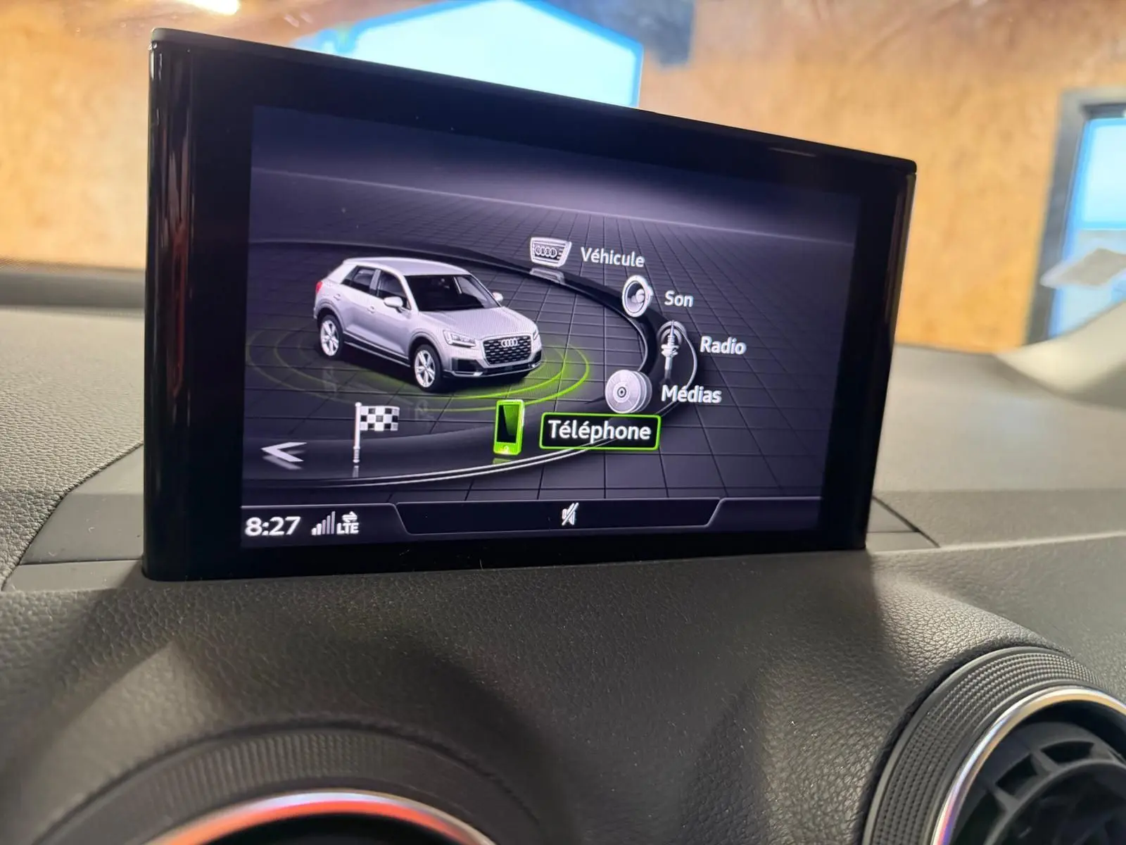 Écran multimédia intérieur montrant un Audi Q2 gris en vue 3/4 avant avec menu de contrôle tactile.