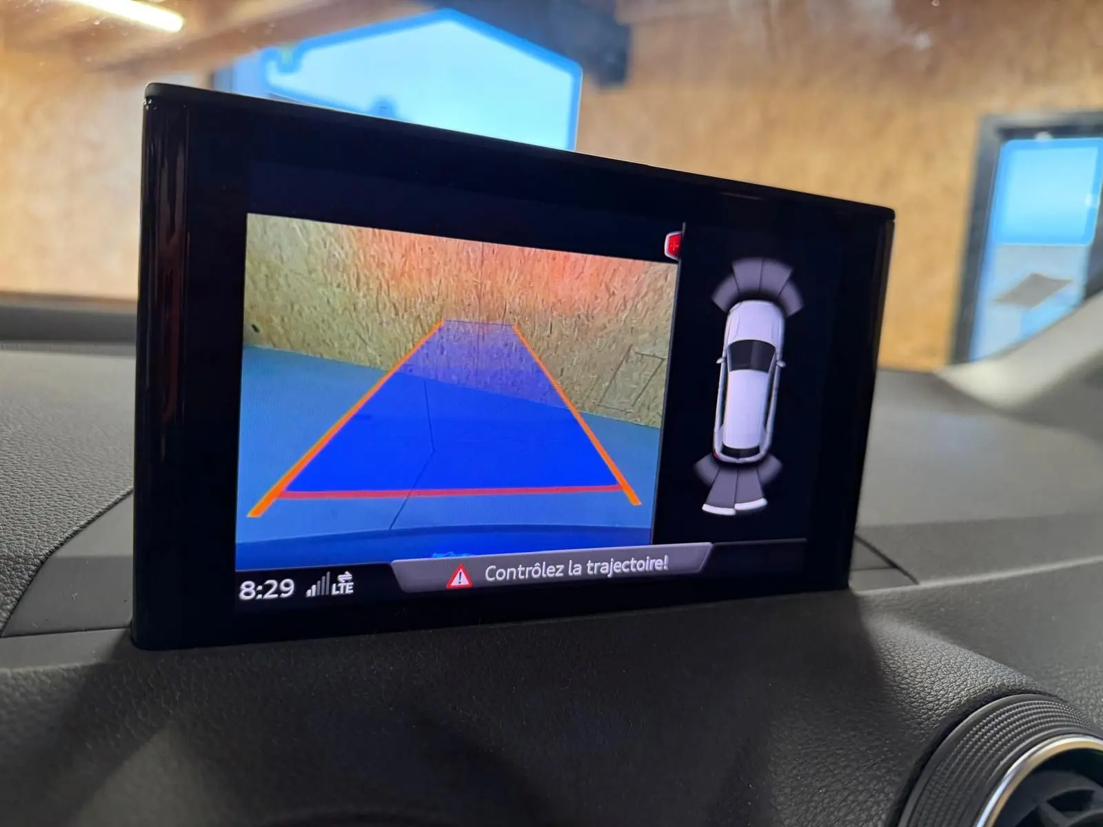 Écran intérieur montrant la caméra de recul et l’aide au stationnement du tableau de bord de l’Audi Q2 gris.