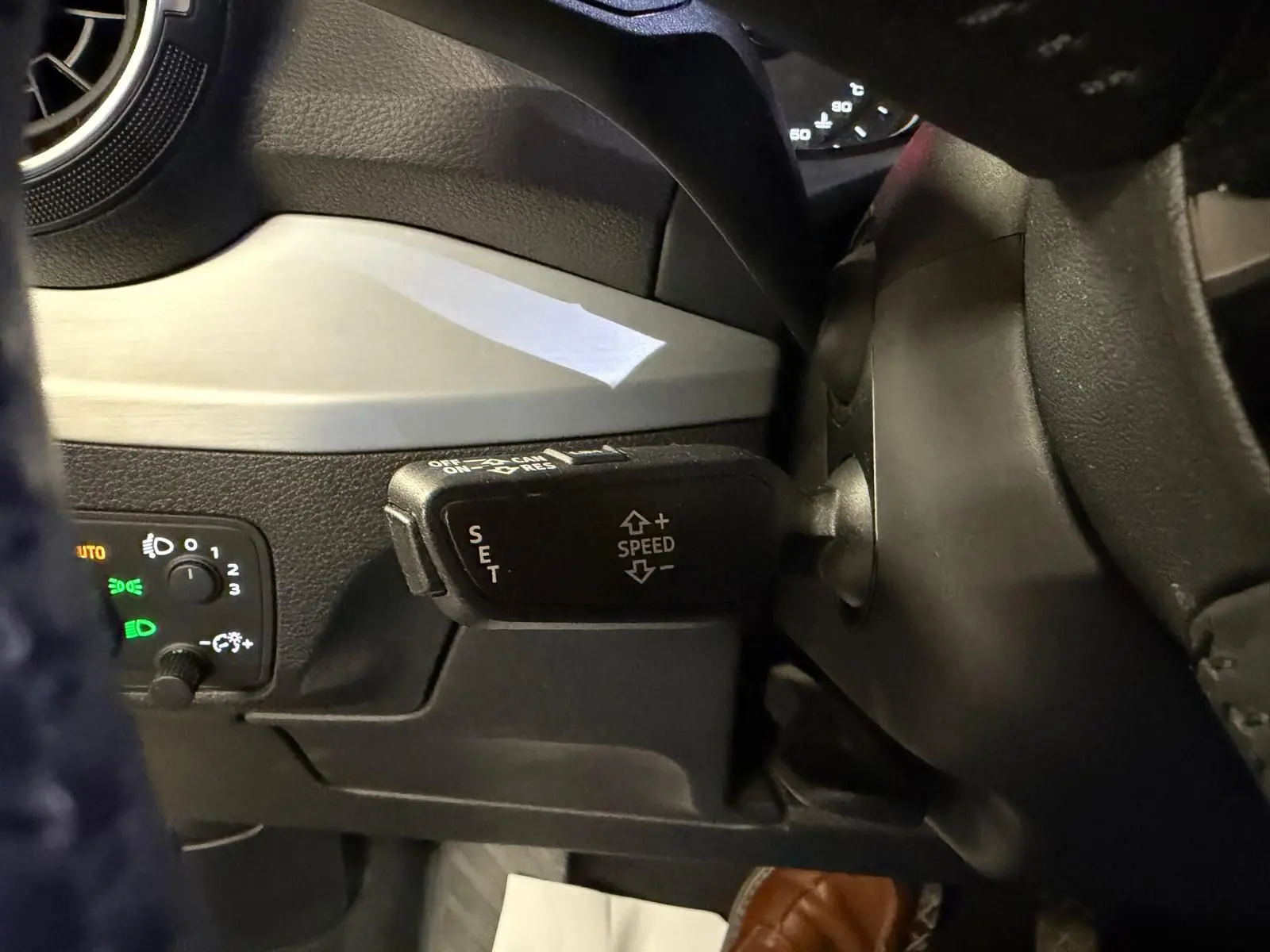 Gros plan sur la commande de régulateur de vitesse au volant cuir de l'Audi Q2 gris, intérieur noir et argenté.