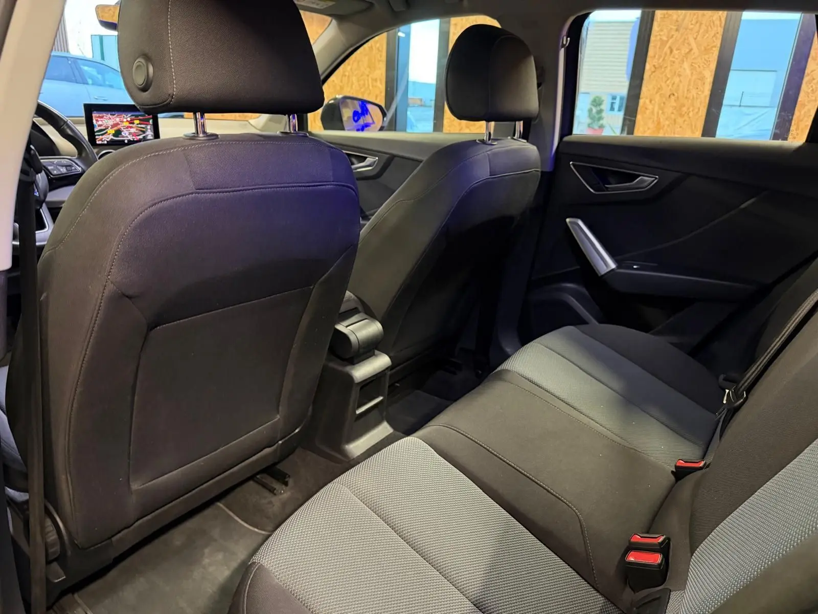 Vue intérieure arrière de l'Audi Q2 2018 avec sièges tissu noir et gris, appuie-têtes et ceintures visibles.