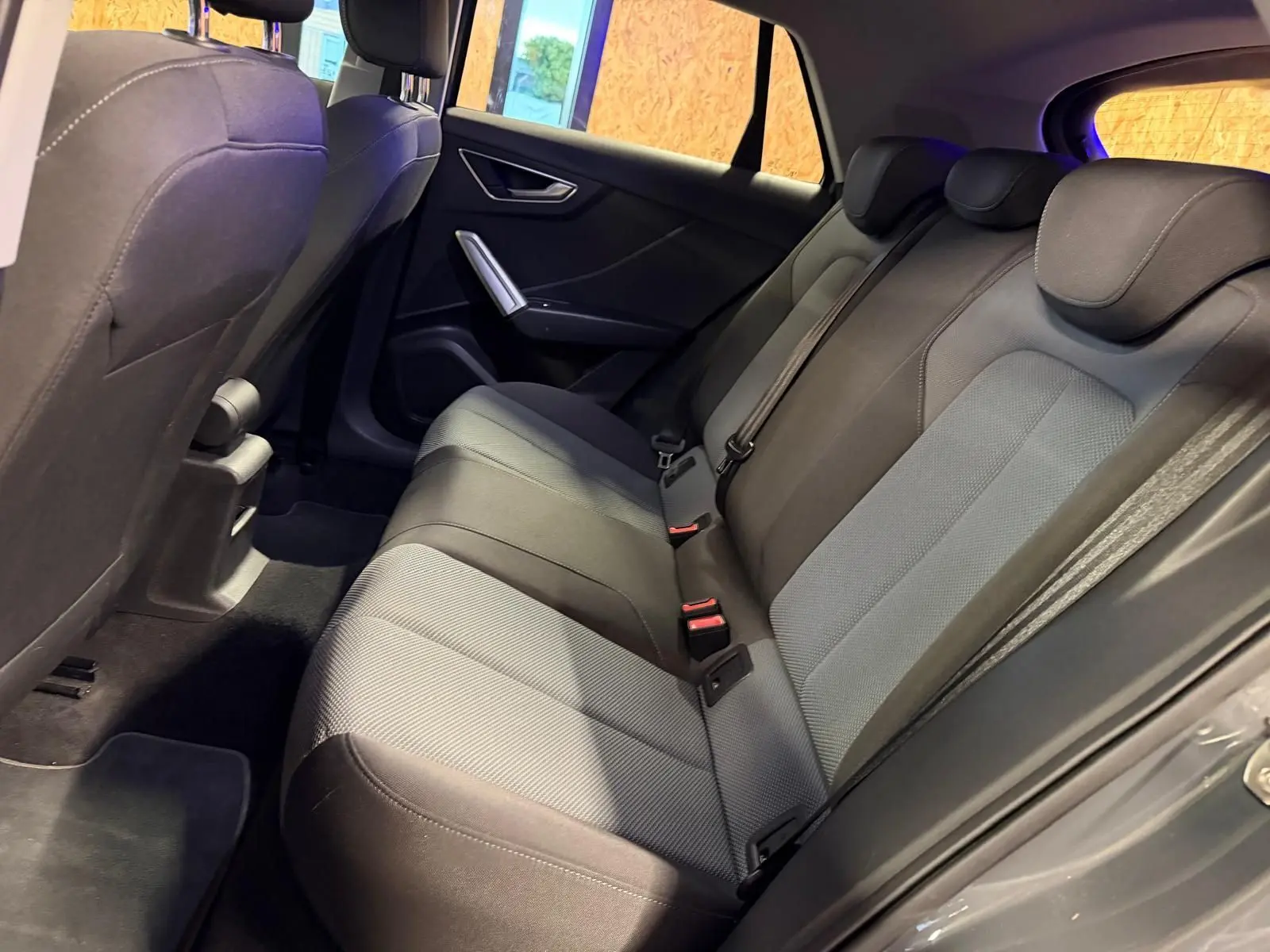 Vue intérieure côté droit de la banquette arrière grise de l'Audi Q2 2018 avec appuie-têtes et ceintures visibles.