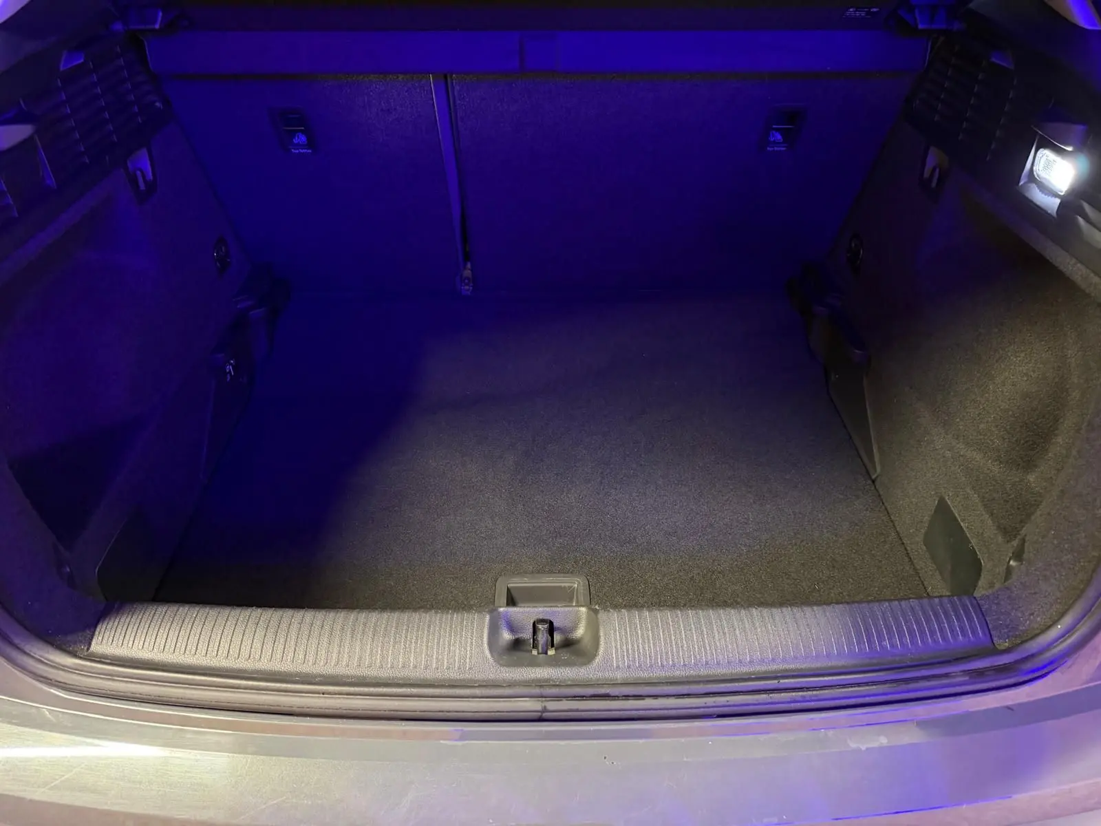 Coffre ouvert d'Audi Q2 gris vu de l'arrière, montrant un espace de chargement propre et éclairé.