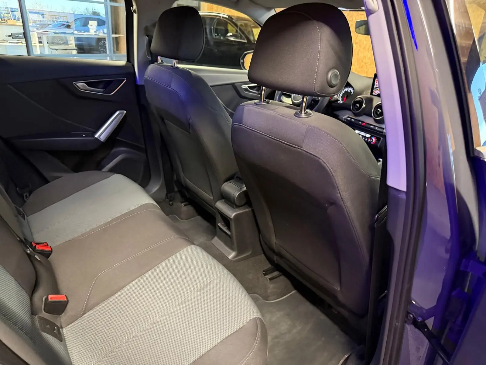 Vue intérieure arrière côté gauche de l'Audi Q2 2018, montrant les sièges tissu bicolore et la portière ouverte.