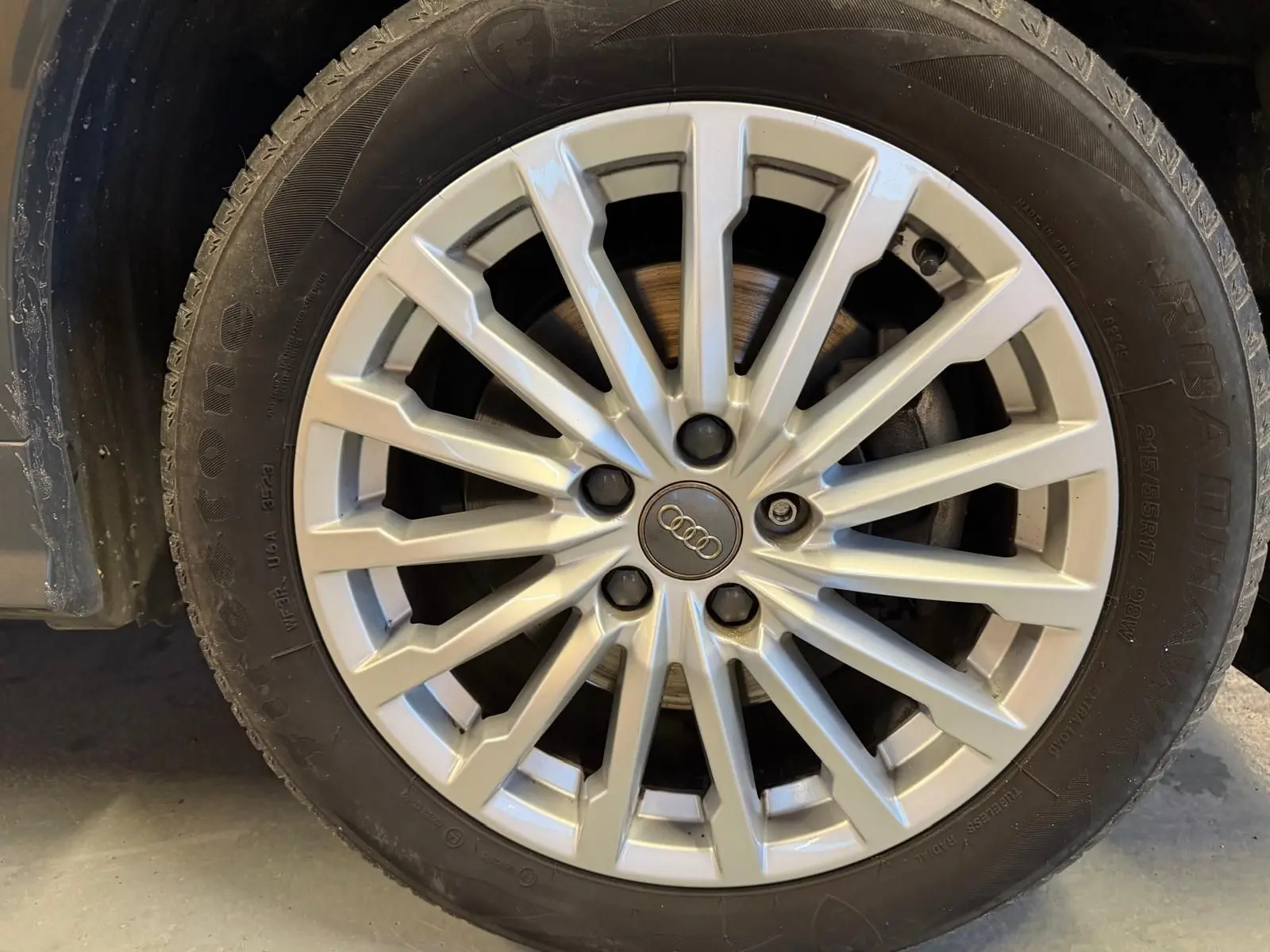 Gros plan sur la jante alu argentée d’un Audi Q2 gris, mettant en valeur le logo Audi au centre.