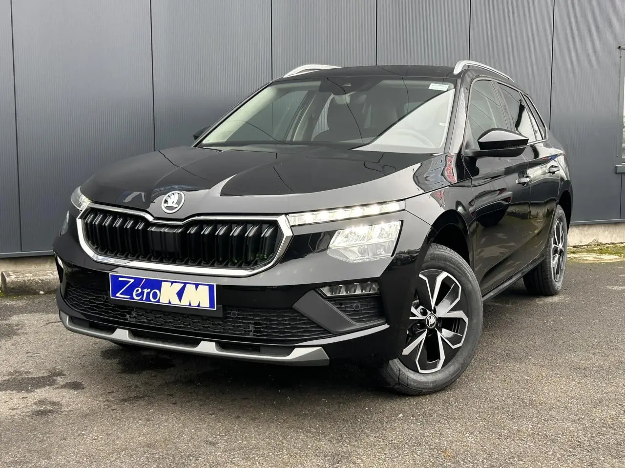 Vue 3/4 avant droit d'un Skoda Kamiq noir Magic avec calandre chromée et jantes alliage 16 pouces.