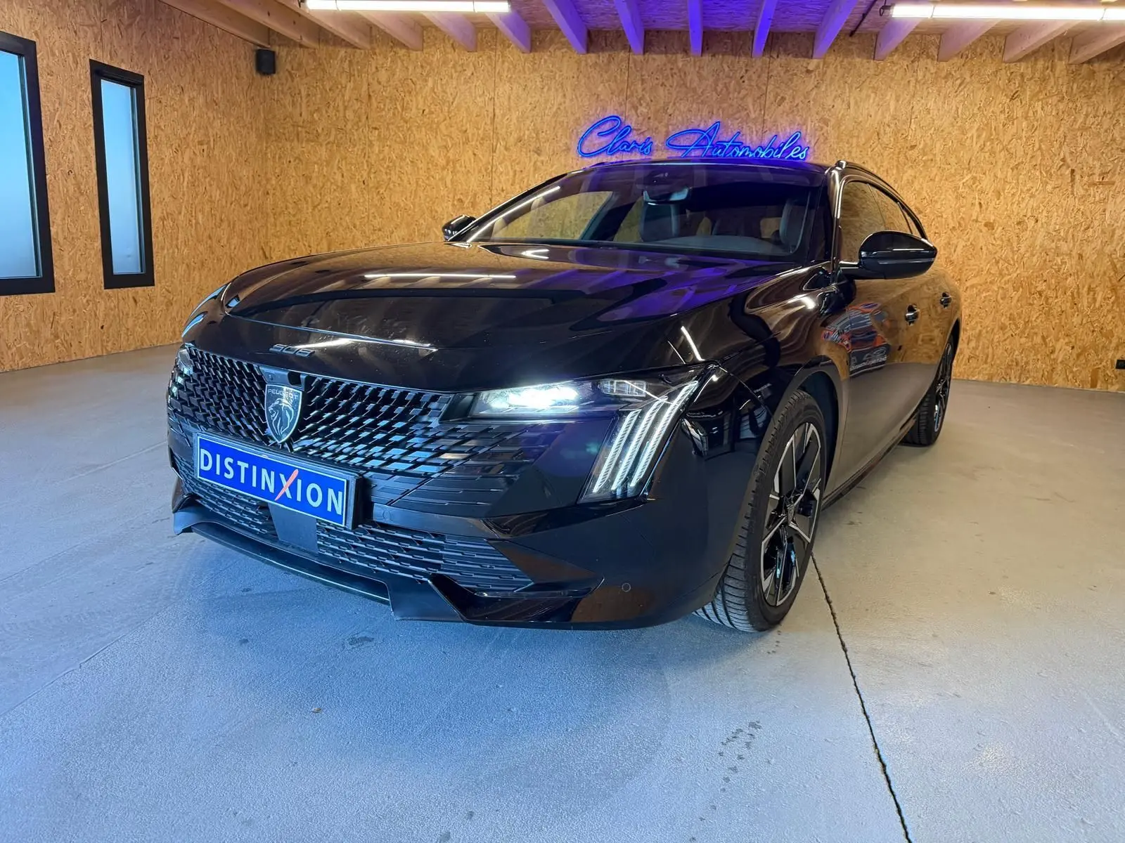 Peugeot 508 SW noire vue 3/4 avant droit avec calandre noire brillante et feux LED allumés en intérieur.