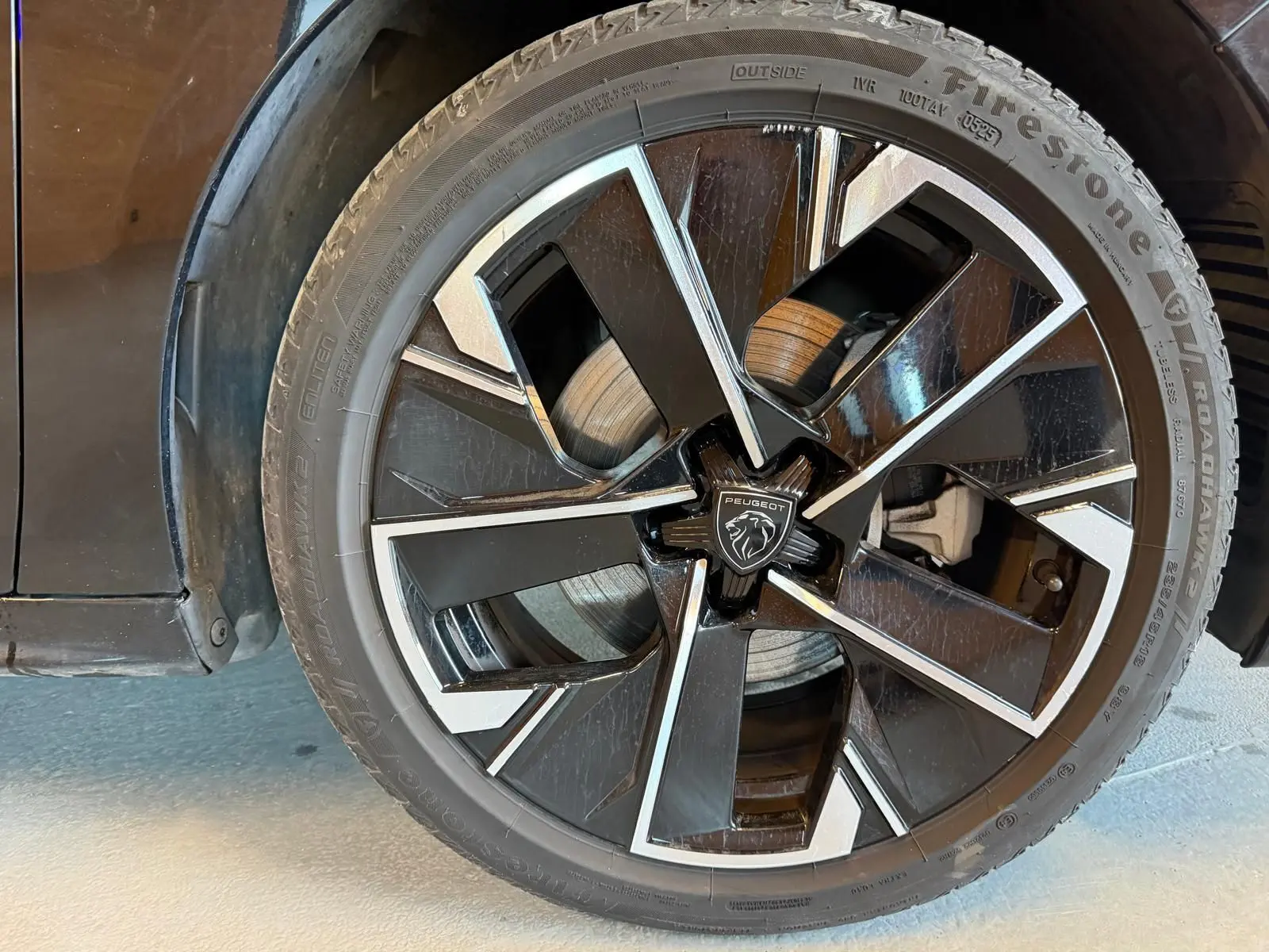 Gros plan sur la jante alliage bi-ton diamantée noire et argentée du côté gauche d'une Peugeot 508 SW noire.