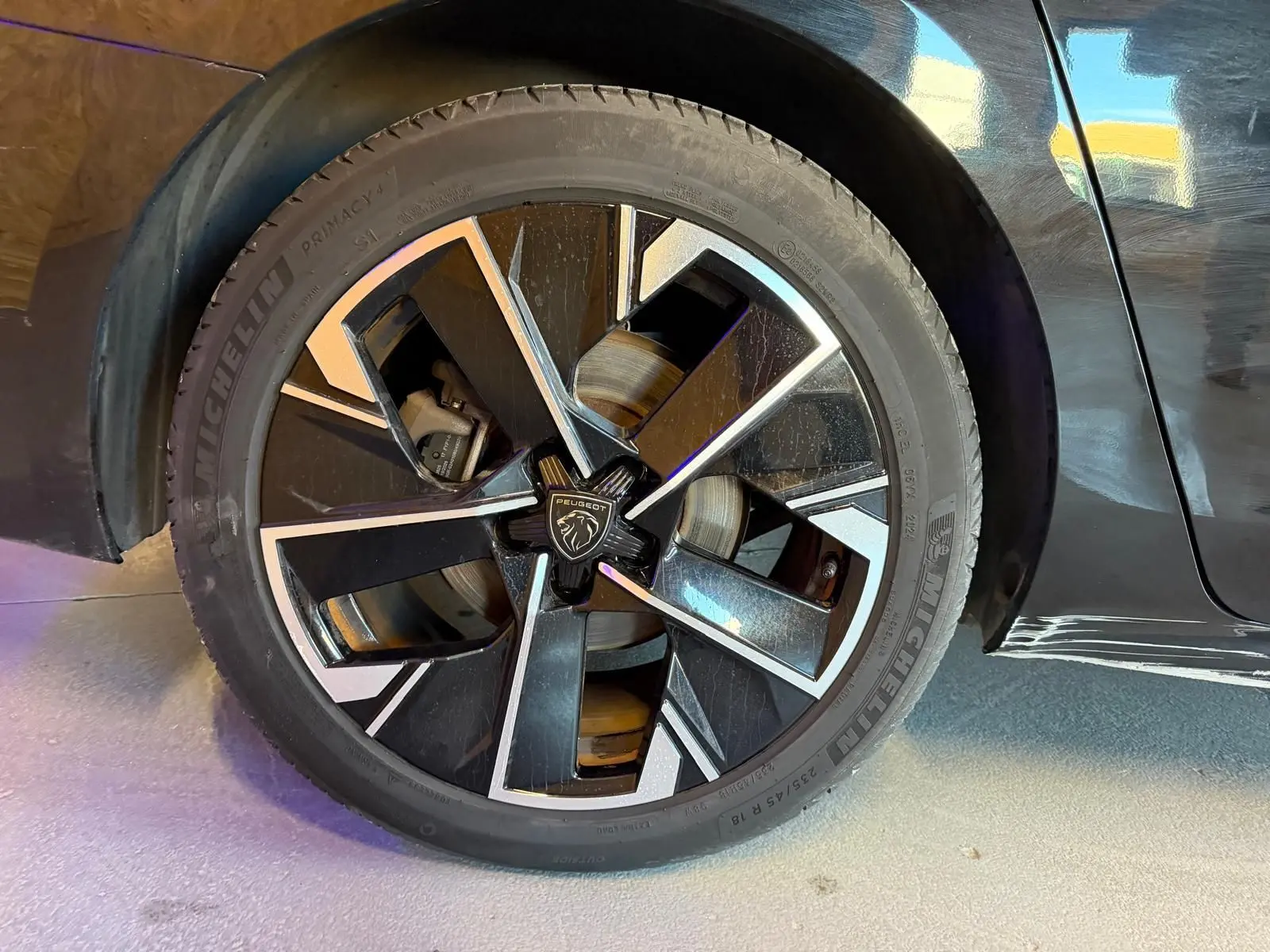 Gros plan sur la jante avant droite noire et argentée diamantée du Peugeot 508 SW noir 2024.