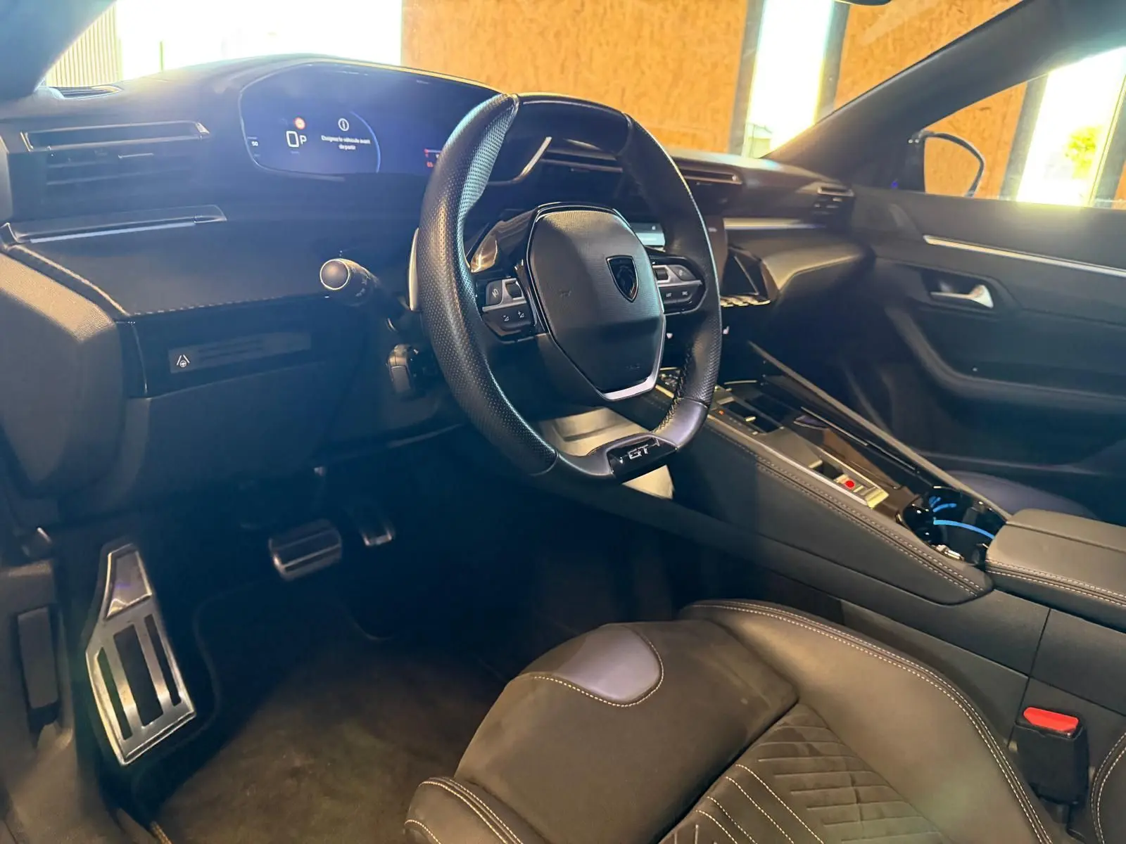 Vue intérieure côté conducteur du Peugeot 508 SW noir, volant GT cuir perforé et planche de bord avec écran numérique.