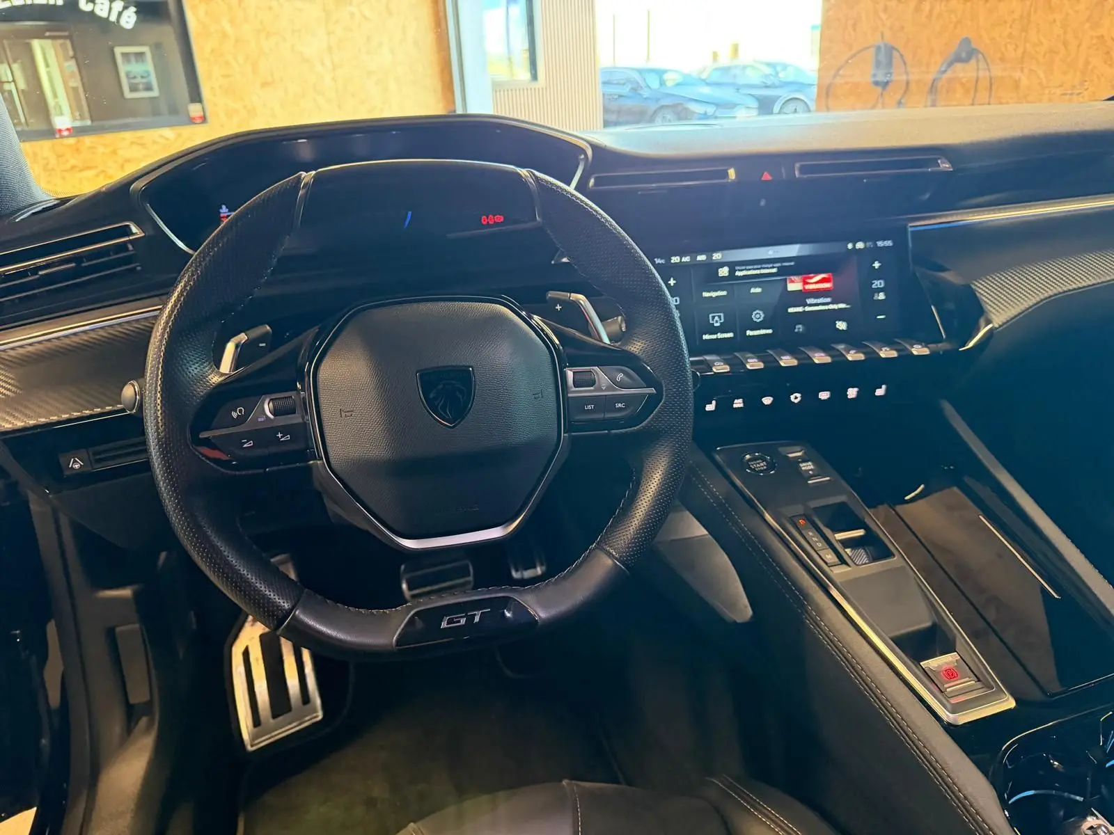 Vue intérieure du poste de conduite du Peugeot 508 SW GT 2024, volant cuir perforé avec badge GT et tableau de bord numérique.