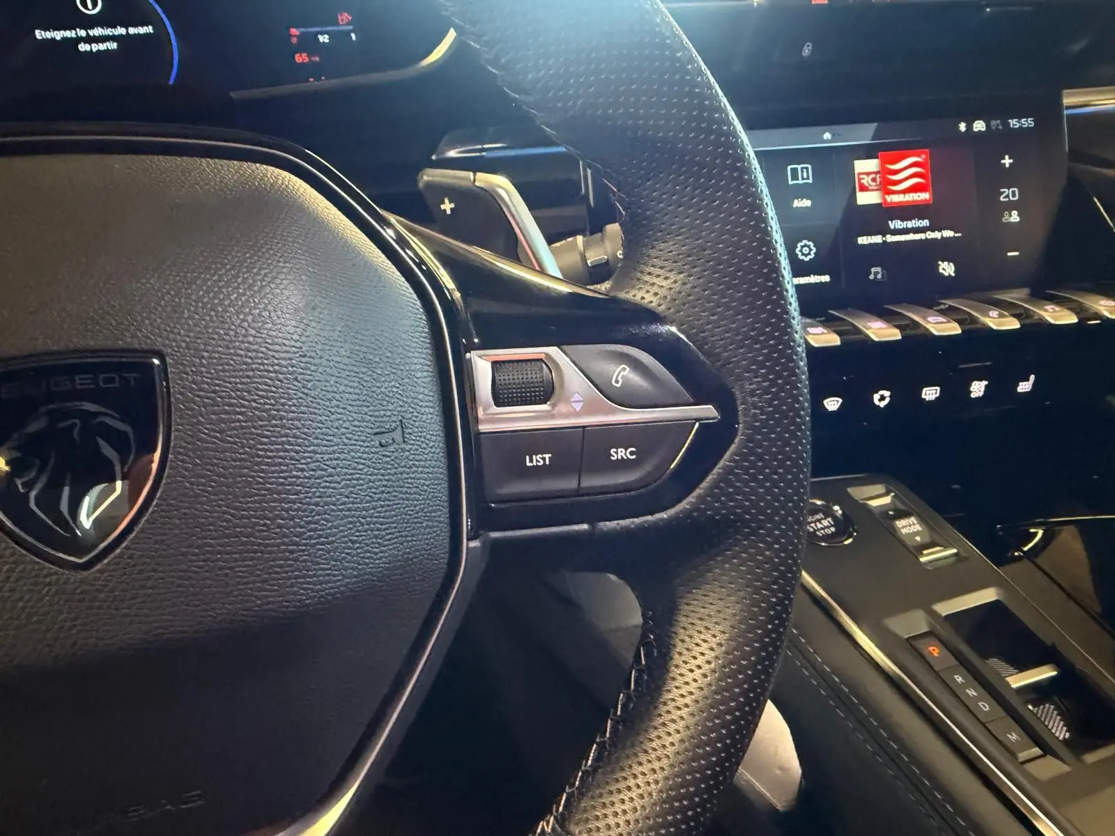 Gros plan sur le volant cuir perforé et la console centrale noire brillante du Peugeot 508 SW 2024, intérieur moderne et high-tech.