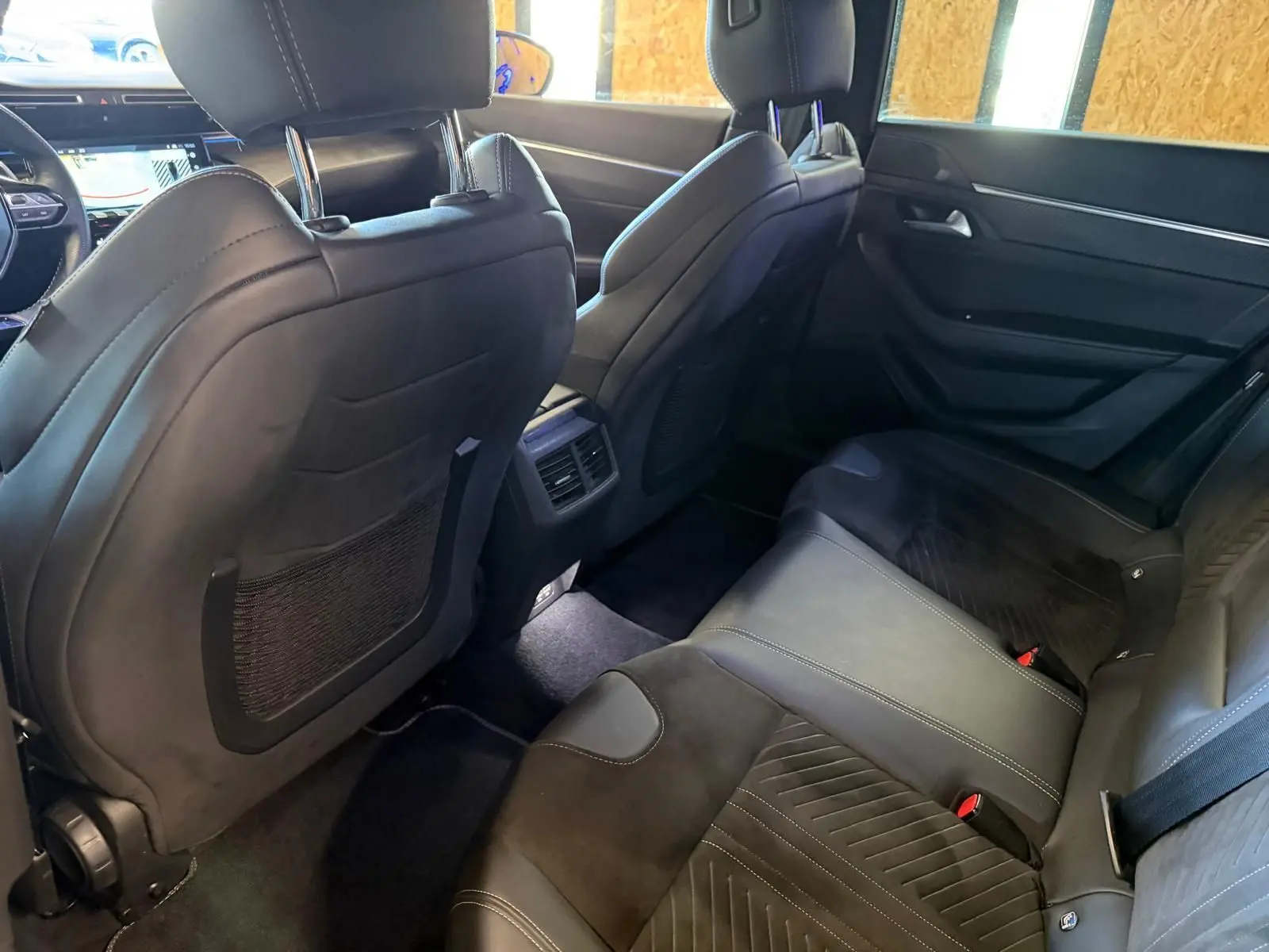 Vue intérieure arrière côté droit de la Peugeot 508 SW 2024, sièges en cuir noir avec surpiqûres et finitions élégantes.
