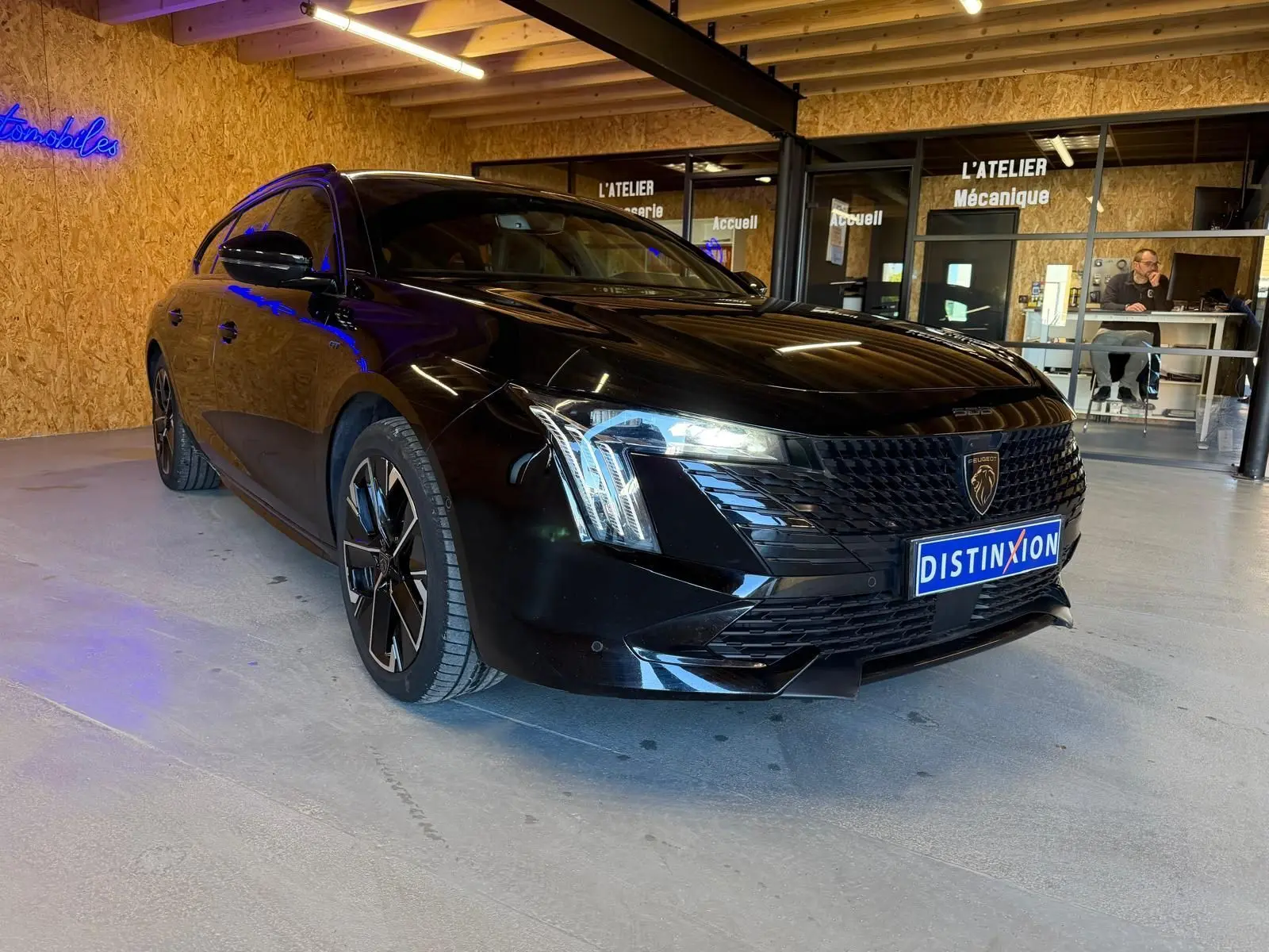 Peugeot 508 SW noire vue 3/4 avant droit, avec calandre noire brillante et jantes alliage bi-ton diamantées.