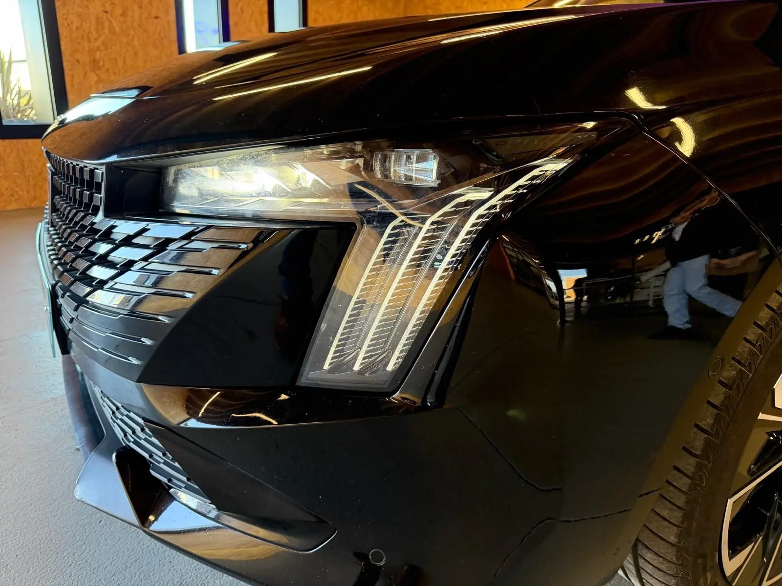 Gros plan sur l'avant droit noir brillant du Peugeot 508 SW 2024, mettant en valeur le phare Matrix LED et la calandre distinctive.