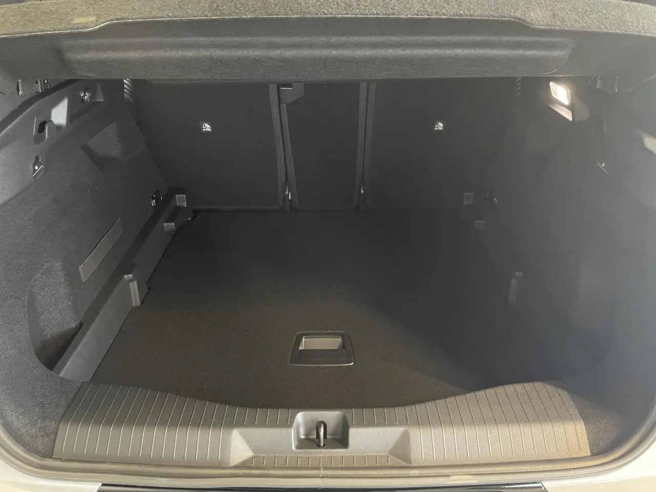 Coffre ouvert vu de l'arrière du Citroën C5 Aircross blanc Okenite avec intérieur noir et éclairage latéral.