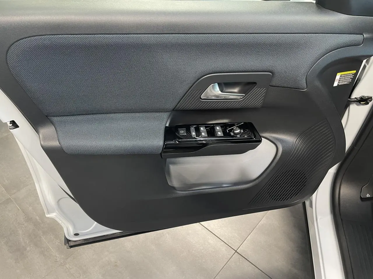 Vue intérieure côté gauche de la porte avant blanche du Citroën C5 Aircross avec commandes de vitres et poignée noire.