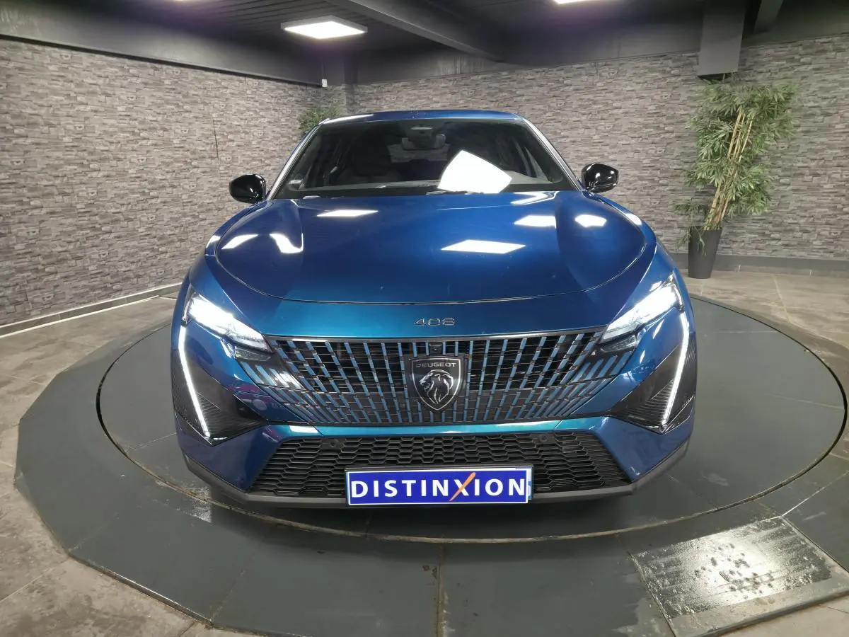 Vue frontale d'une Peugeot 408 berline GT bleu métallisé avec calandre noire et feux LED griffés allumés.