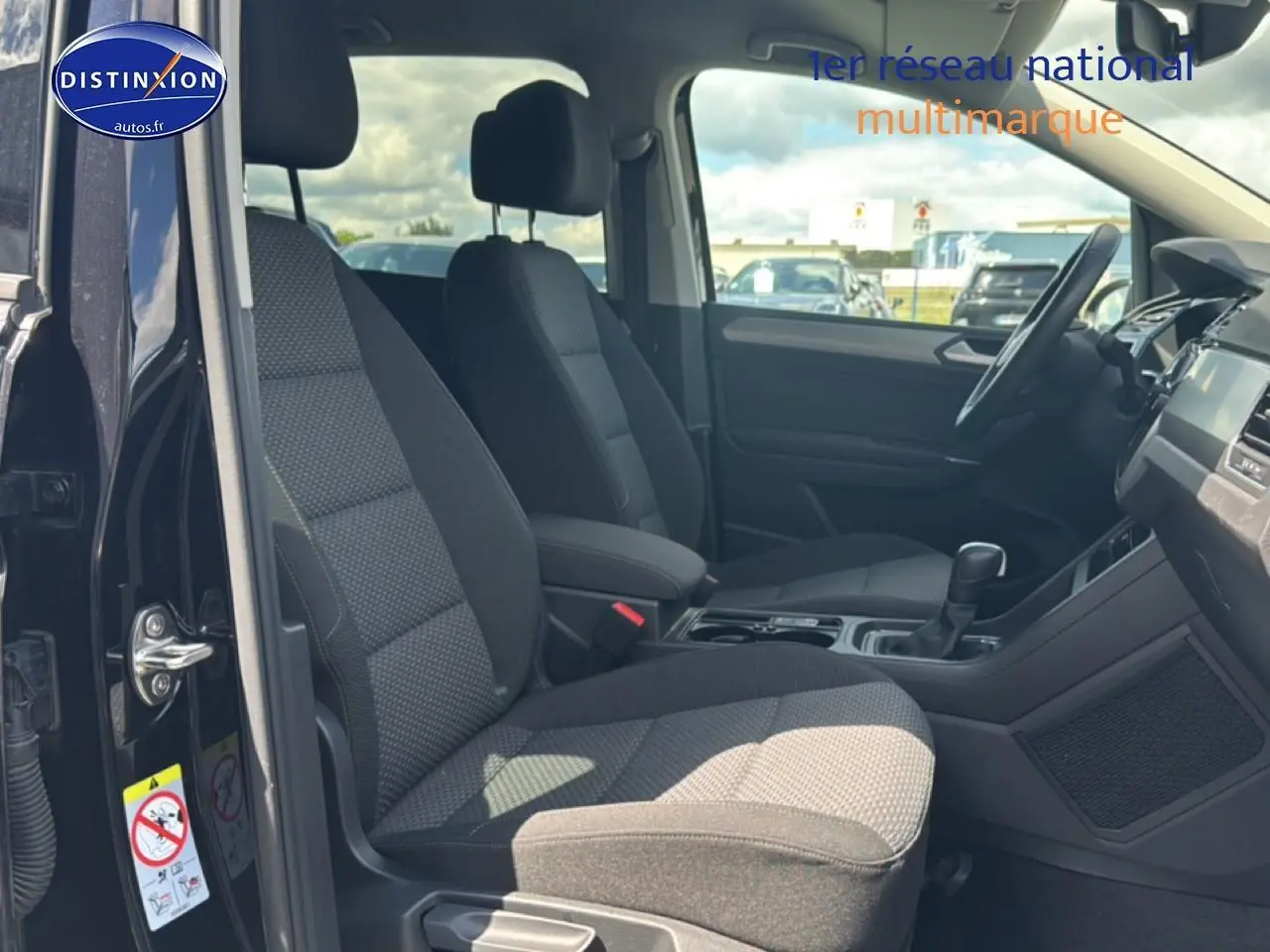 Vue intérieure côté gauche du Volkswagen Touran noir 2025, montrant les sièges avant et la console centrale.