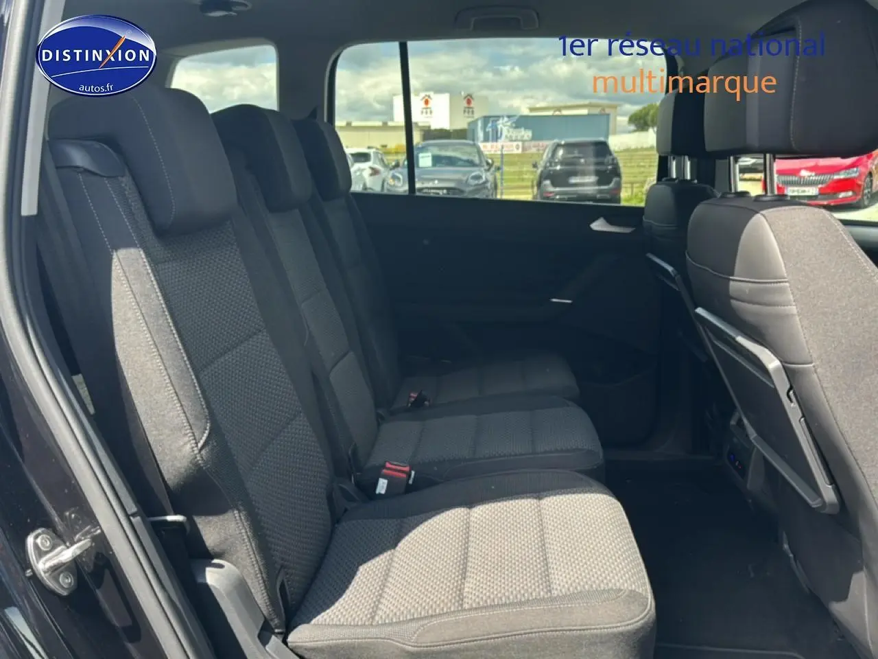 Vue latérale intérieure montrant les sièges tissu gris du rang 2 du Volkswagen Touran noir 2025 avec 7 places.
