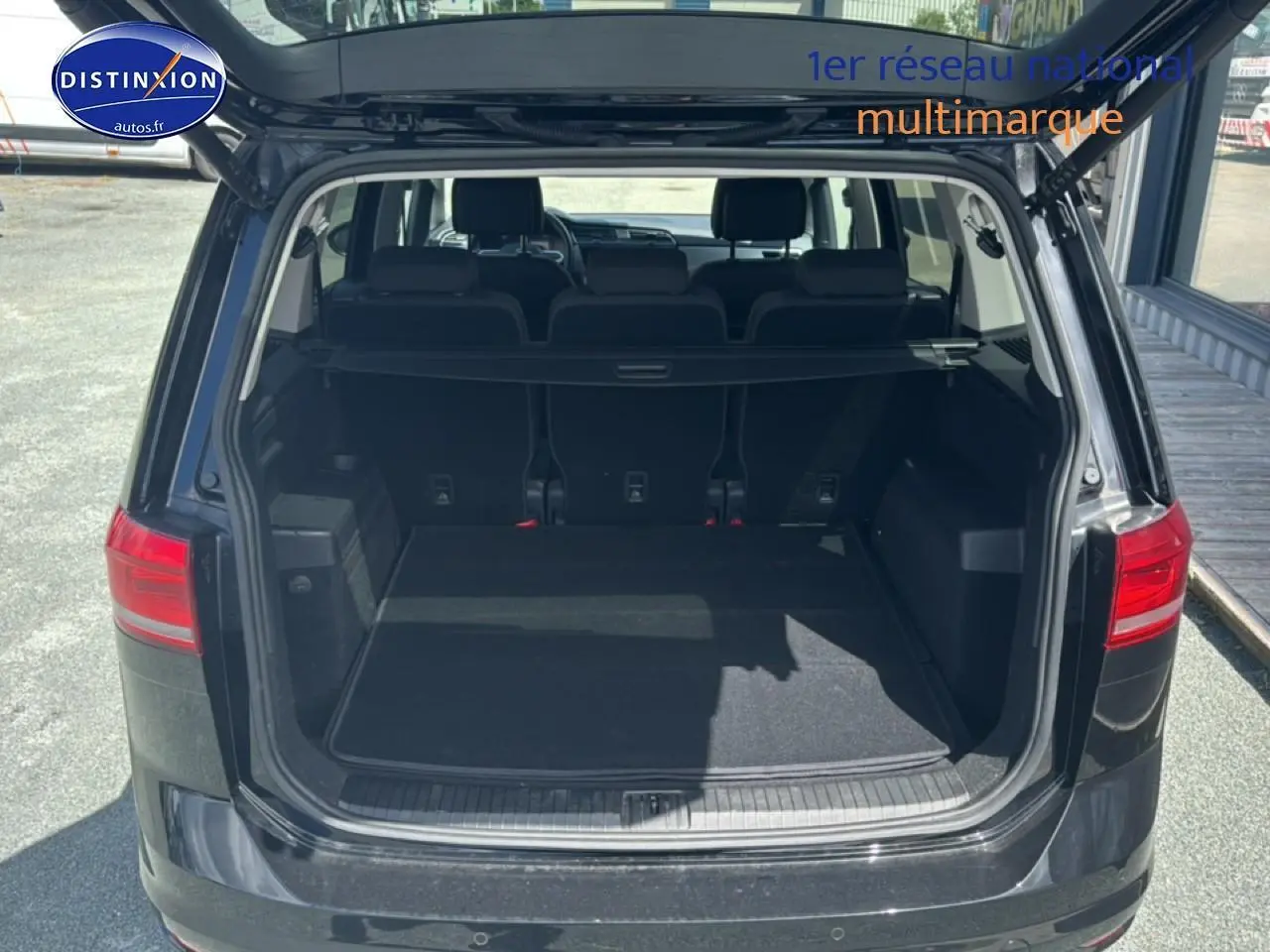 Vue arrière ouverte du coffre noir d’un Volkswagen Touran 2025 avec la troisième rangée de sièges visible.