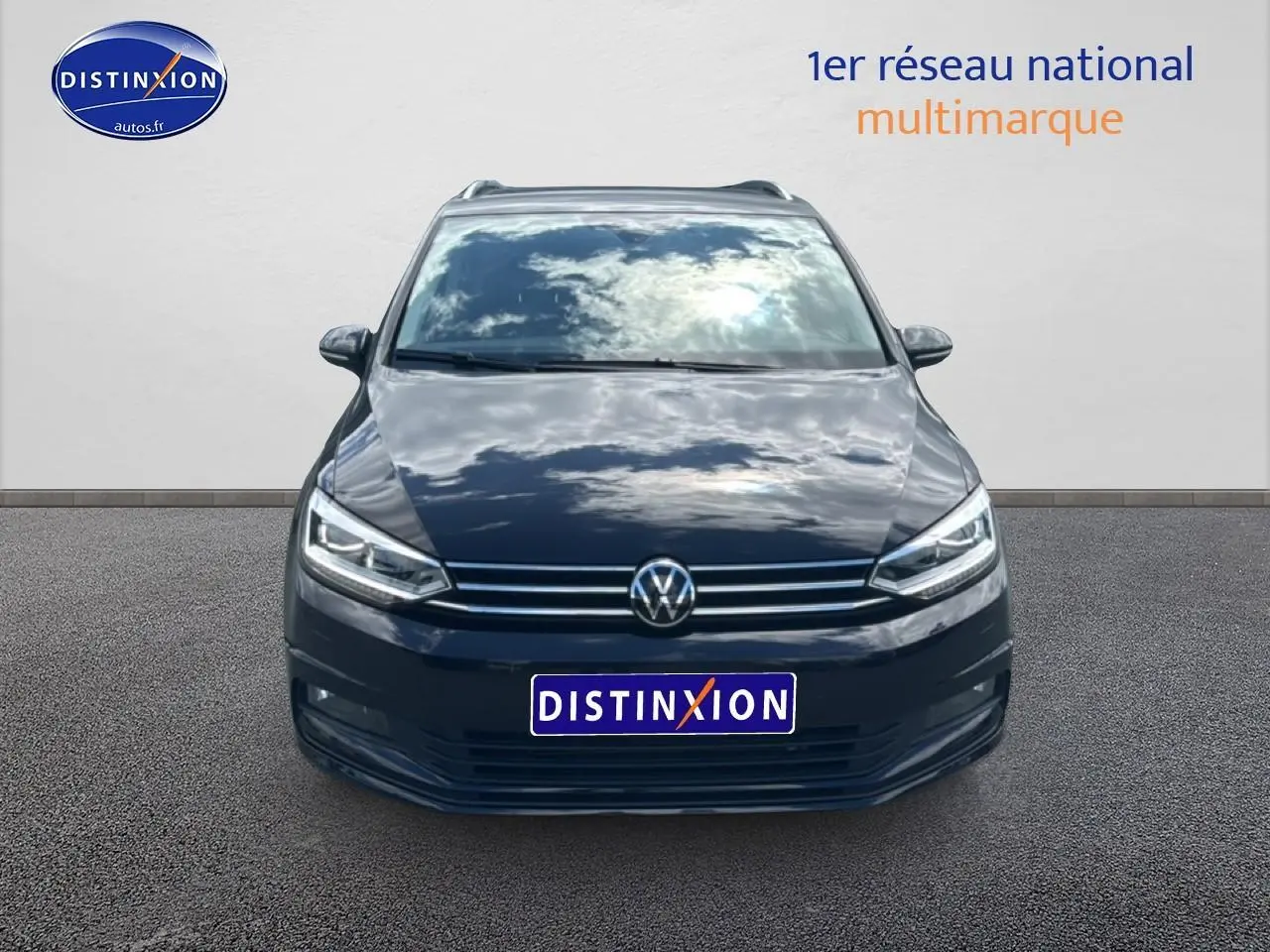 Vue frontale d'un Volkswagen Touran noir 2025 avec calandre chromée et phares LED allumés.