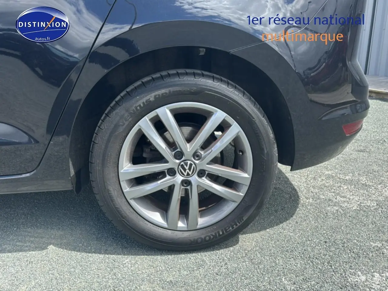 Gros plan sur la roue arrière droite d'un Volkswagen Touran noir avec jante alu cinq branches.