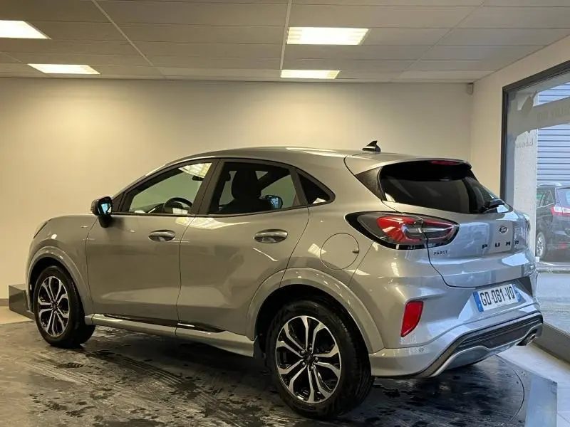 Ford Puma gris Solar métallisée vue 3/4 arrière droit en intérieur, avec vitres arrière surteintées et jantes alu noires.