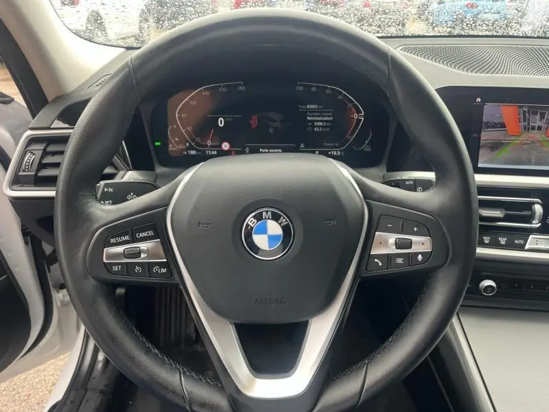 Vue rapprochée du volant cuir multifonction BMW Série 3 316dA 2021 avec tableau de bord numérique et écran de caméra de recul.