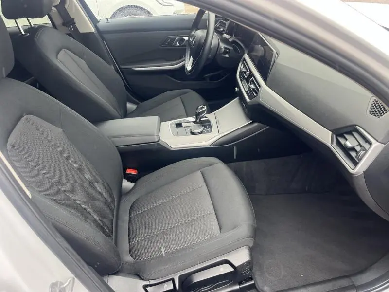 Intérieur avant droit de BMW Série 3 316dA 2021 avec sièges sport en tissu noir et console centrale moderne grise.