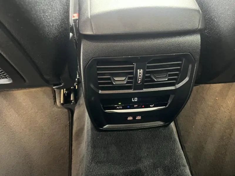 Vue rapprochée de la console arrière noire avec aérateurs et commandes de climatisation de la BMW Série 3 blanche.