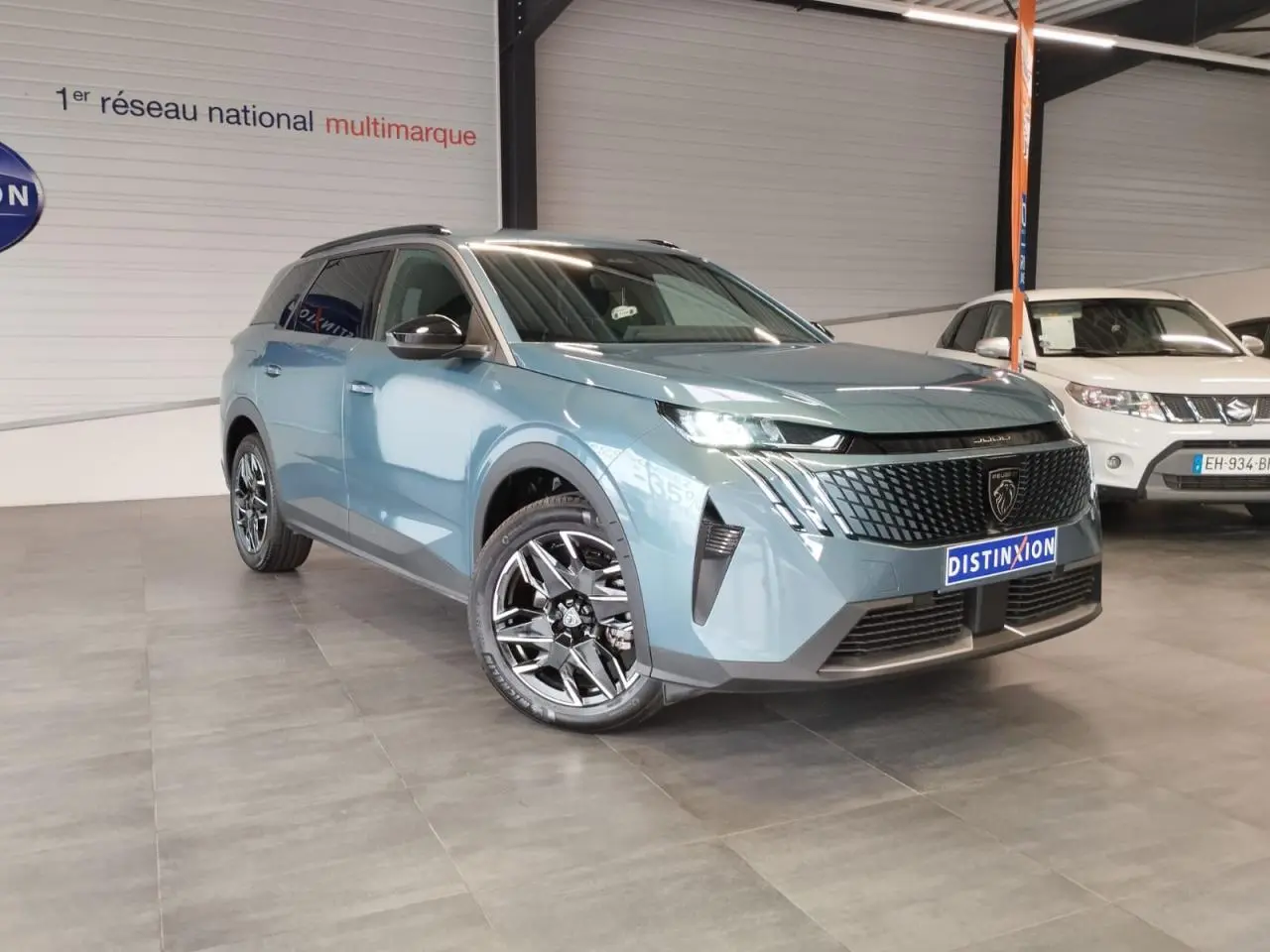 Peugeot 5008 bleu Ingaro en 3/4 avant droit, avec calandre noire et jantes alliage 19 pouces diamantées.