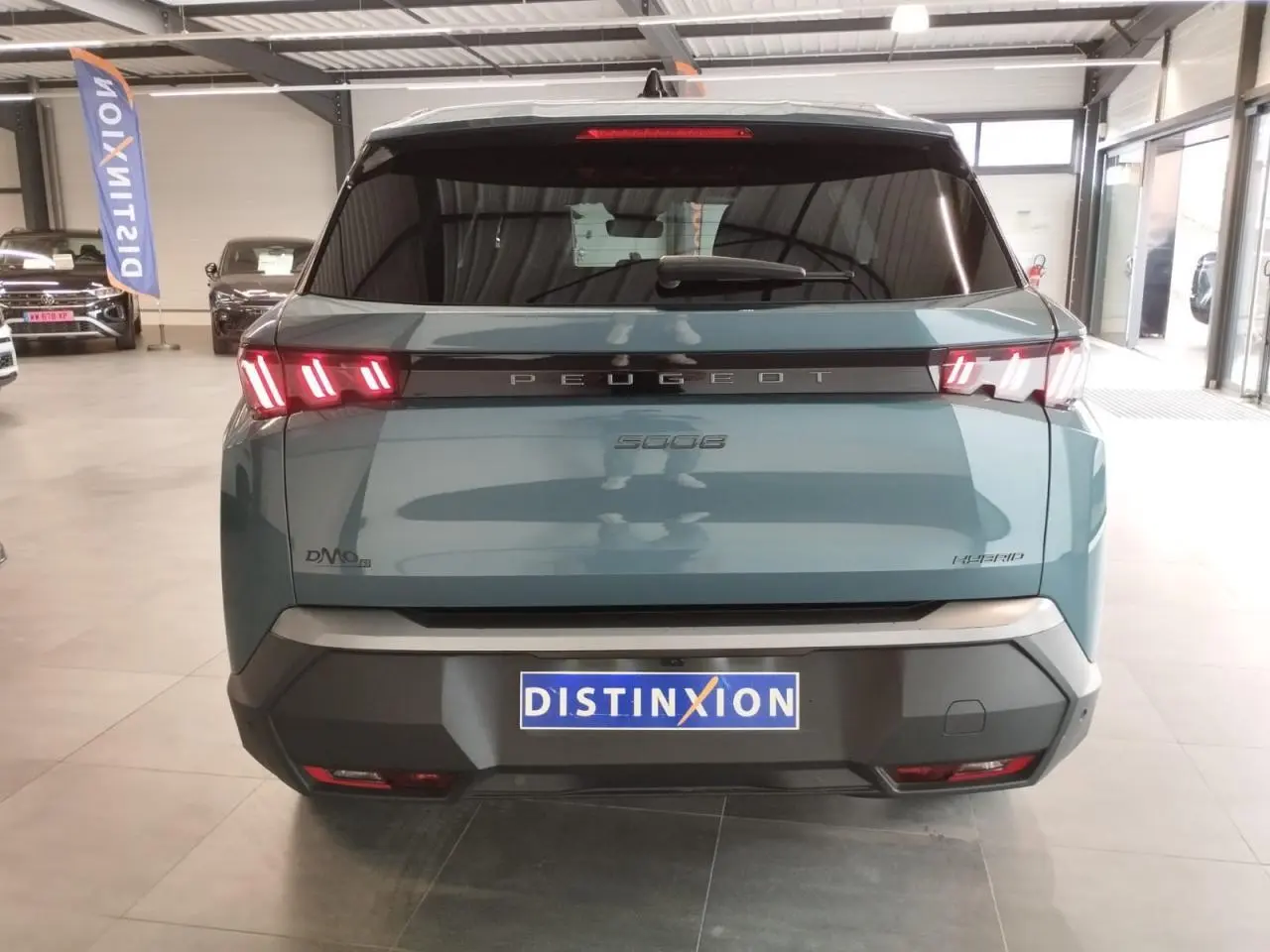 Vue arrière d'un Peugeot 5008 Hybrid bleu Ingaro avec feux arrière LED à 3 griffes et bandeau noir laqué.