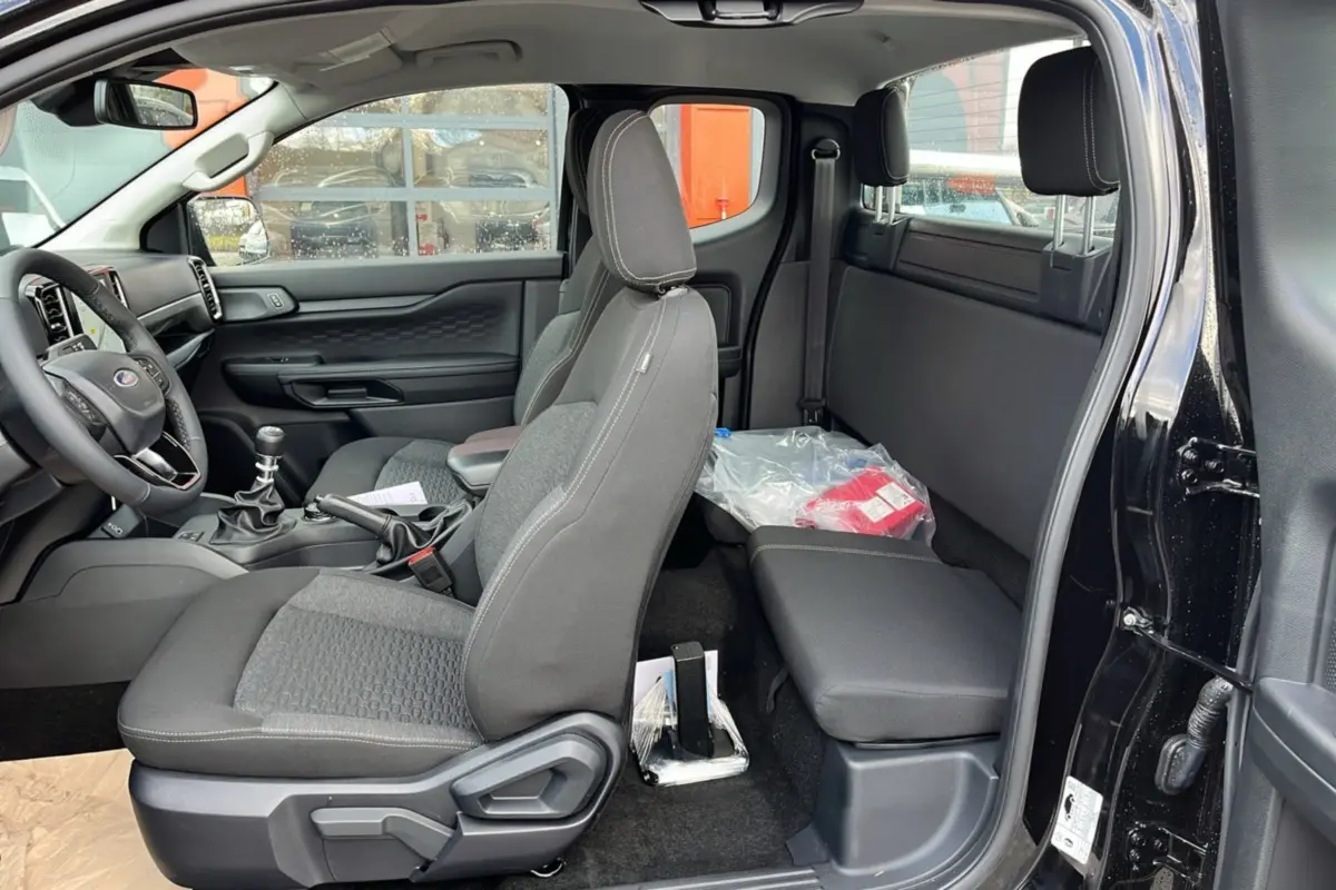 Vue intérieure côté gauche du Ford Ranger noir shadow 2025, montrant les sièges avant, banquette arrière et tableau de bord.