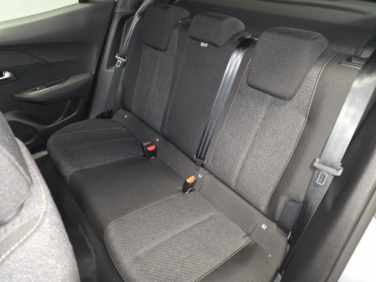 Vue intérieure côté droit montrant la banquette arrière tissu noir avec surpiqûres orange du Peugeot 2008 gris 2025.