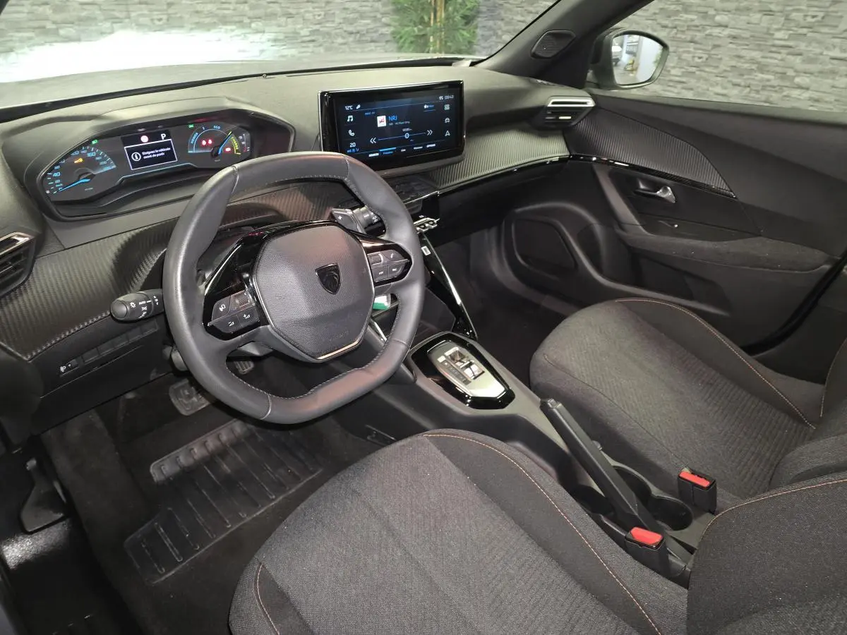 Intérieur avant du Peugeot 2008 gris, vue côté conducteur, avec tableau de bord numérique et écran tactile central.