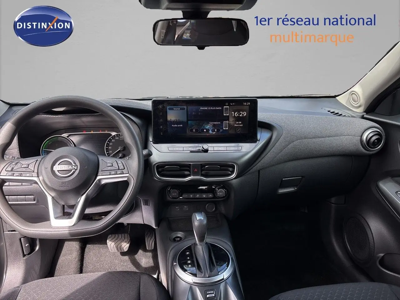 Vue intérieure avant du tableau de bord et volant du Nissan Juke Hybrid 2024 avec écran tactile central et finition noire.