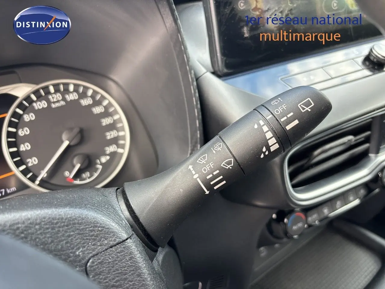 Gros plan sur la commande d’essuie-glace à droite du volant du Nissan Juke gris squale métal 2024, tableau de bord partiellement visible.