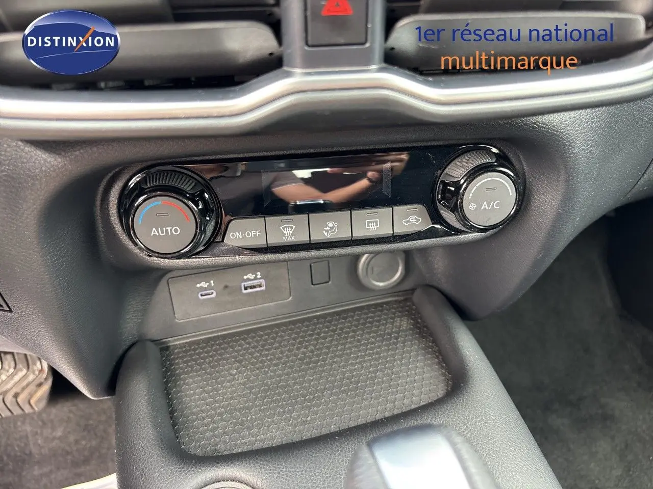 Vue rapprochée de la console centrale du Nissan Juke 2024, montrant les commandes de climatisation et ports USB.