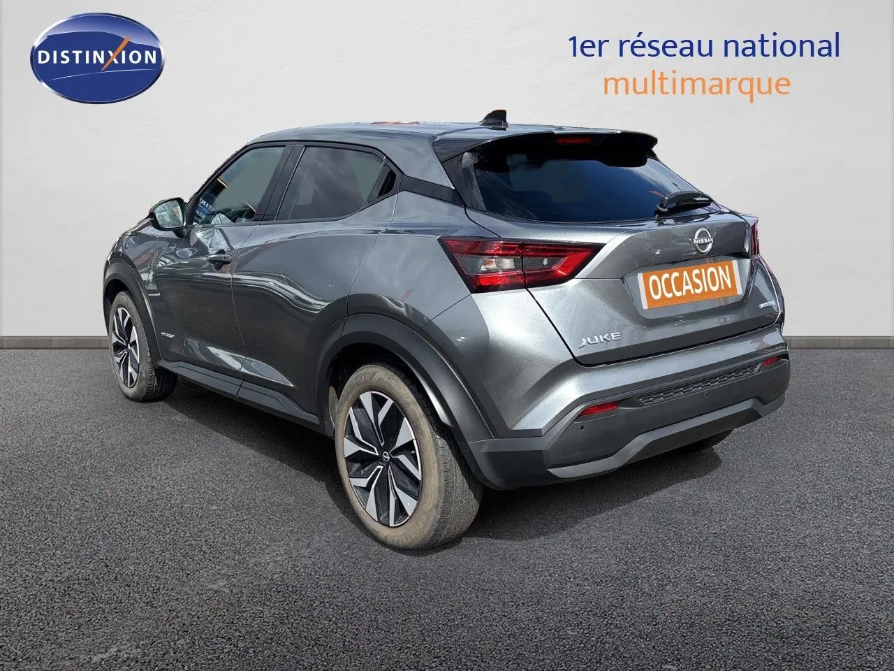 Nissan Juke Hybrid gris squale metal, vue 3/4 arrière droit, avec jantes alliage et vitres teintées.