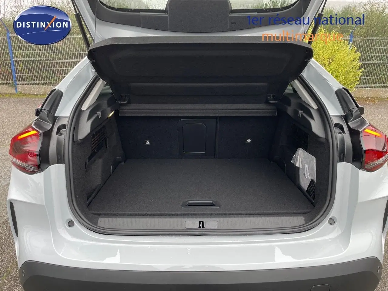 Coffre ouvert vu de l'arrière d'une Citroën C4 blanche métal 2024, avec feux arrière allumés et intérieur spacieux.