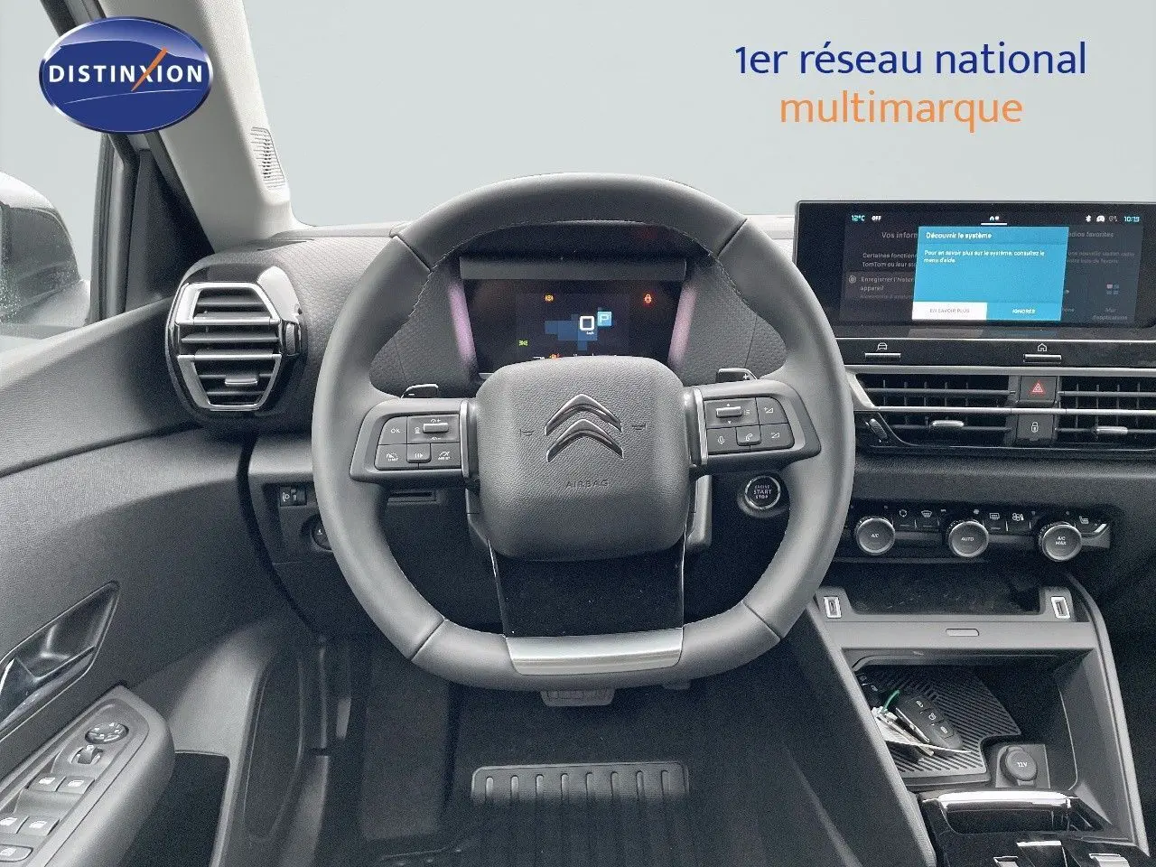 Intérieur de la Citroën C4 2024 vu de face, volant multifonction et écran tactile central allumé.