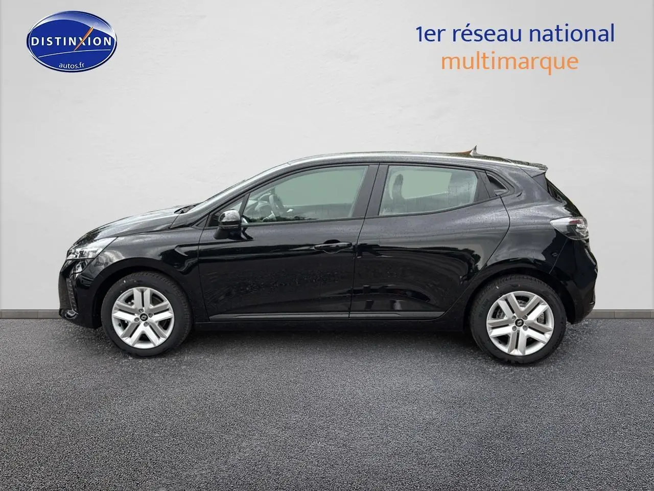 Profil côté gauche d'une Renault Clio V noire 2025 avec jantes argentées, stationnée devant un mur blanc.