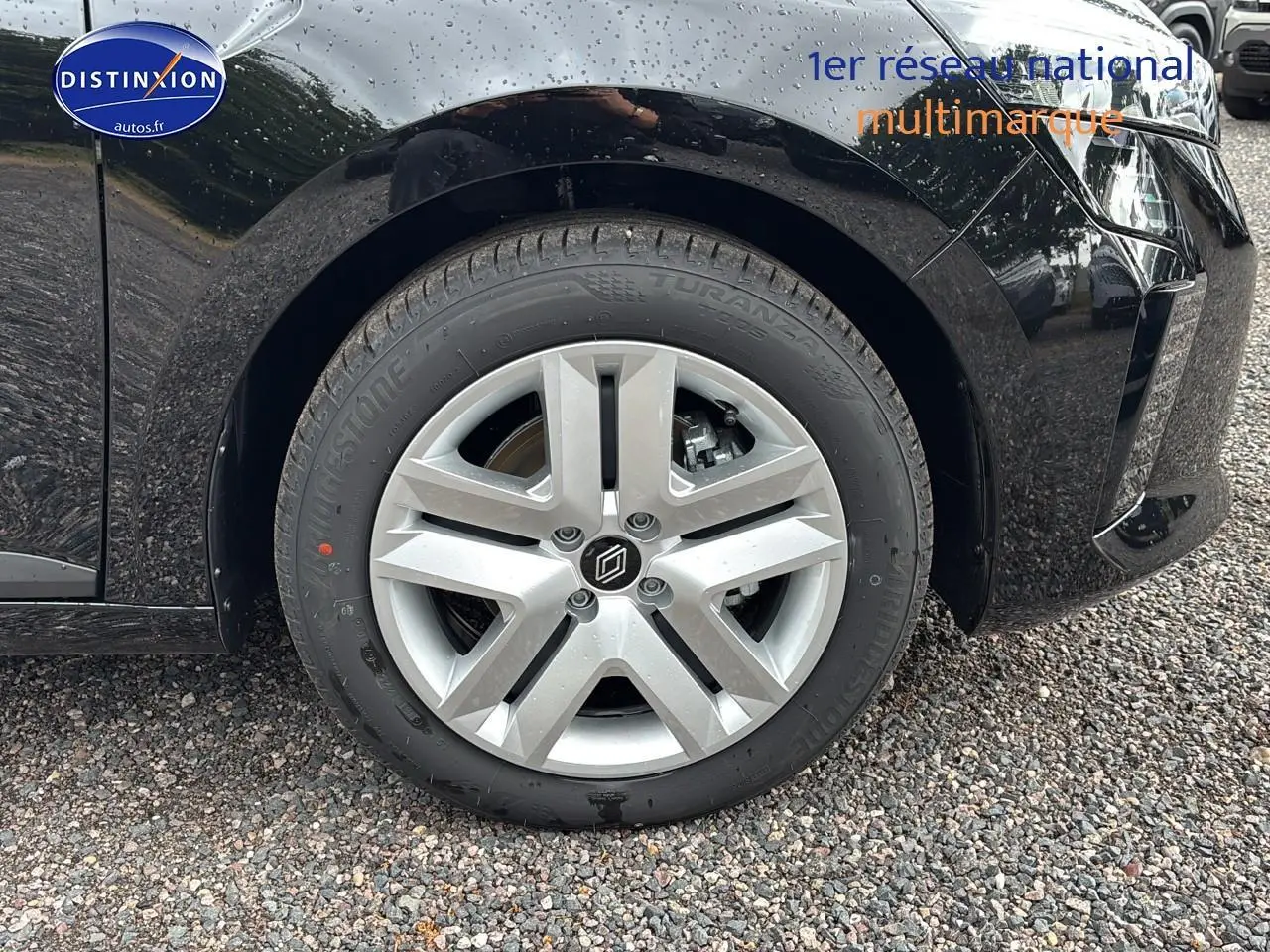 Gros plan sur la roue avant gauche de la Renault Clio V noire avec jante argentée et logo central distinctif.