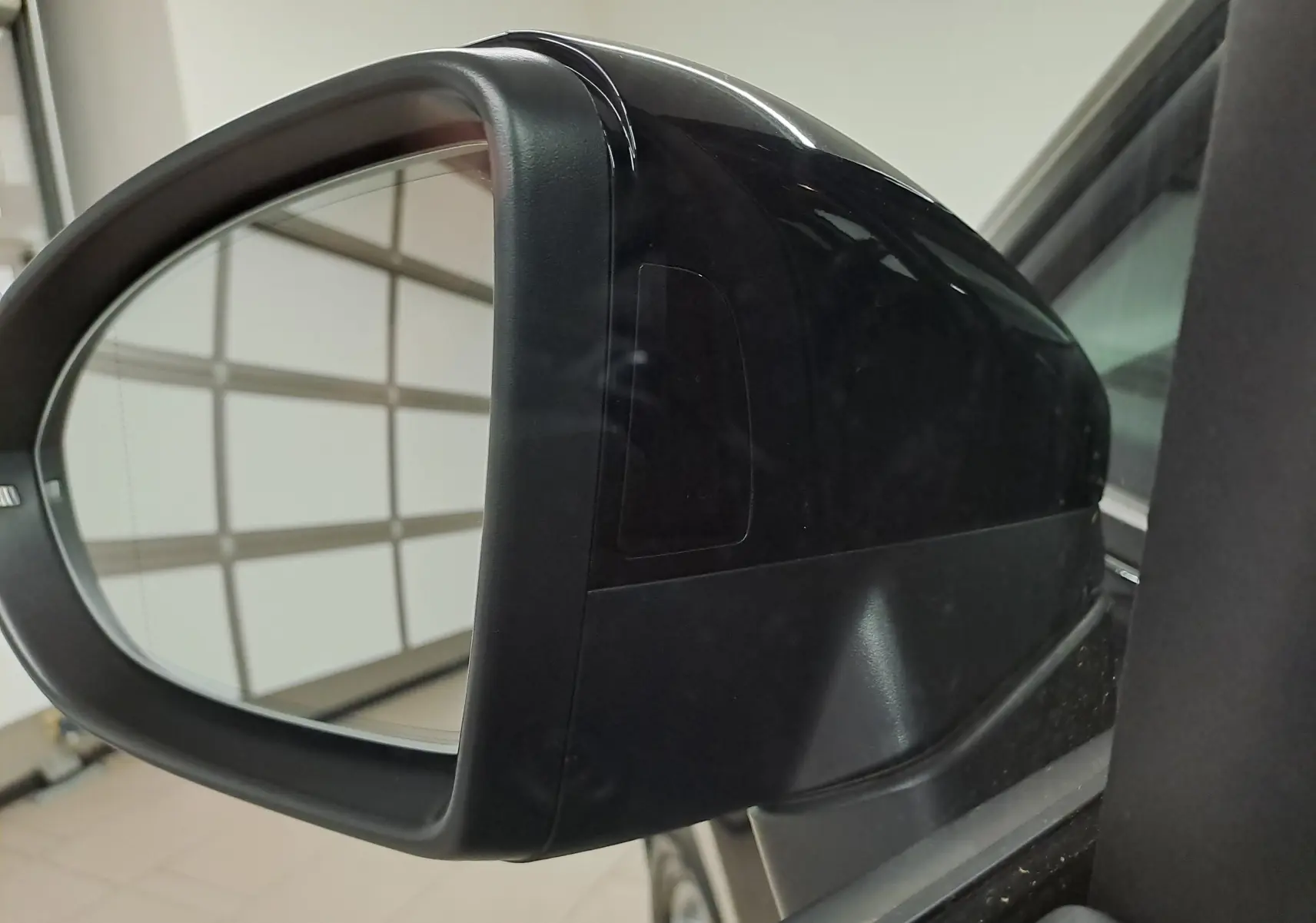 Rétroviseur extérieur droit noir grenadille du Volkswagen Touran 2025, vue rapprochée en intérieur de garage.