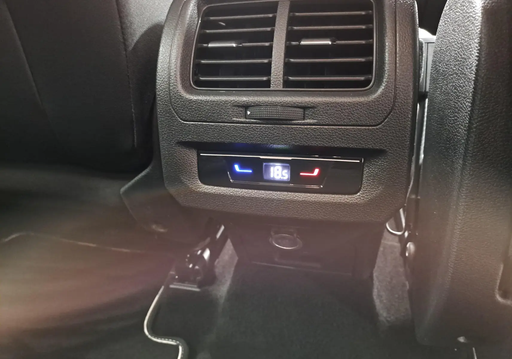 Détail de la console arrière du Volkswagen Touran 2025 noir Grenadille avec réglage numérique de la climatisation à 18,5°C.