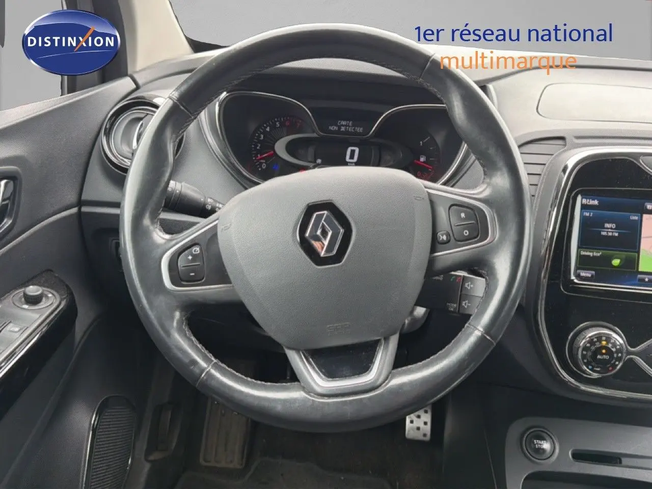 Vue rapprochée du volant en cuir noir avec logo Renault et tableau de bord numérique du Captur gris Cassiopée.