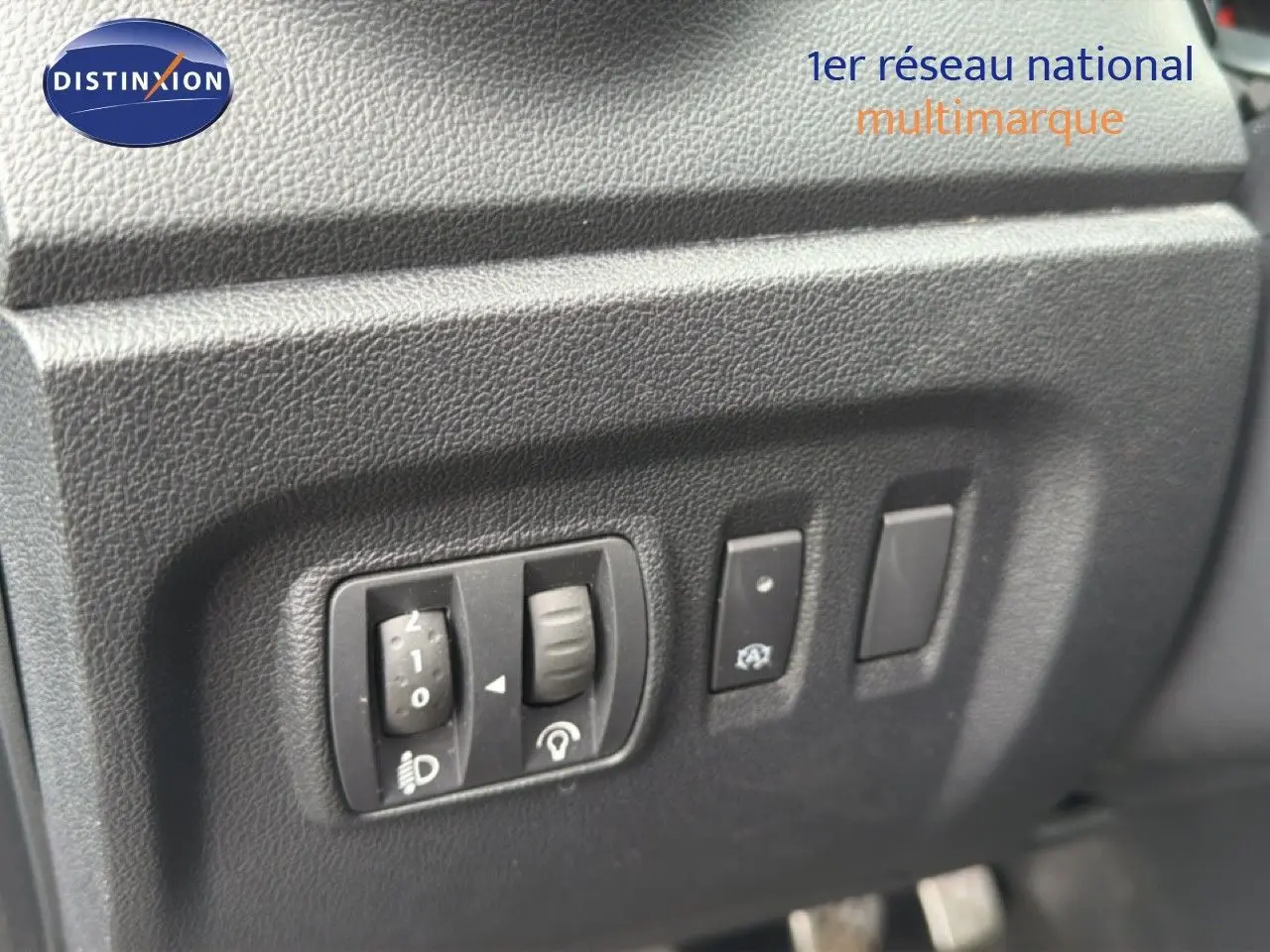 Gros plan sur les commandes d'éclairage et d'assistance du tableau de bord d'un Renault Captur gris Cassiopée.