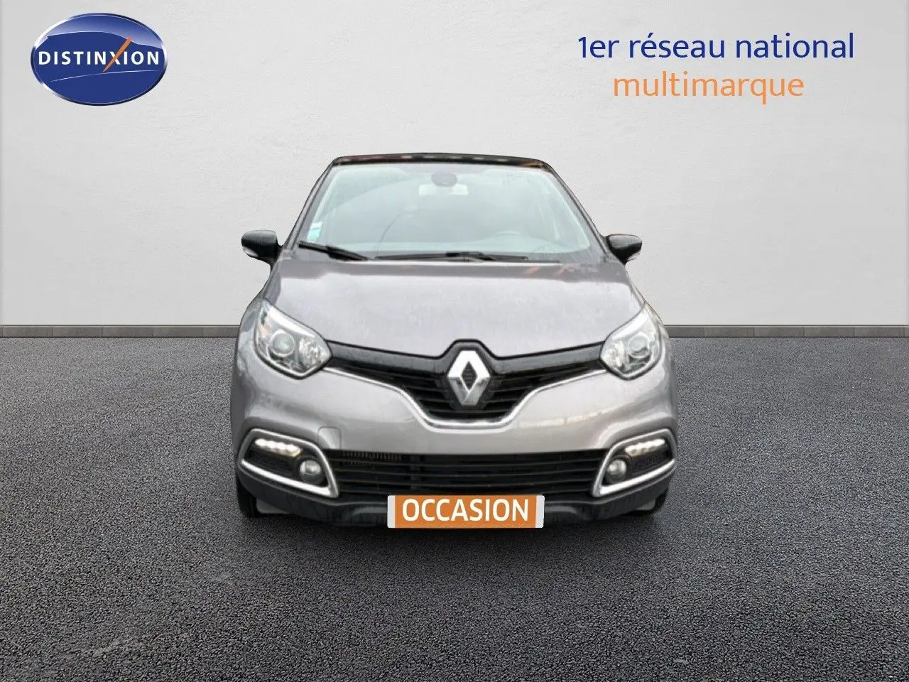 Vue frontale d'une Renault Captur gris Cassiopée avec toit noir étoilé, feux diurnes LED allumés, sur fond neutre.