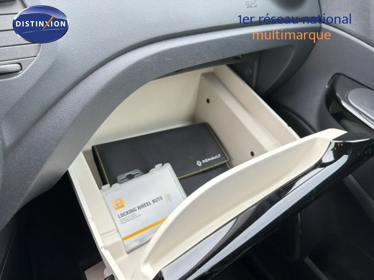 Gant de boîte à gants ouvert intérieur beige et noir avec pochette Renault et boîte d'écrous antivol visible.